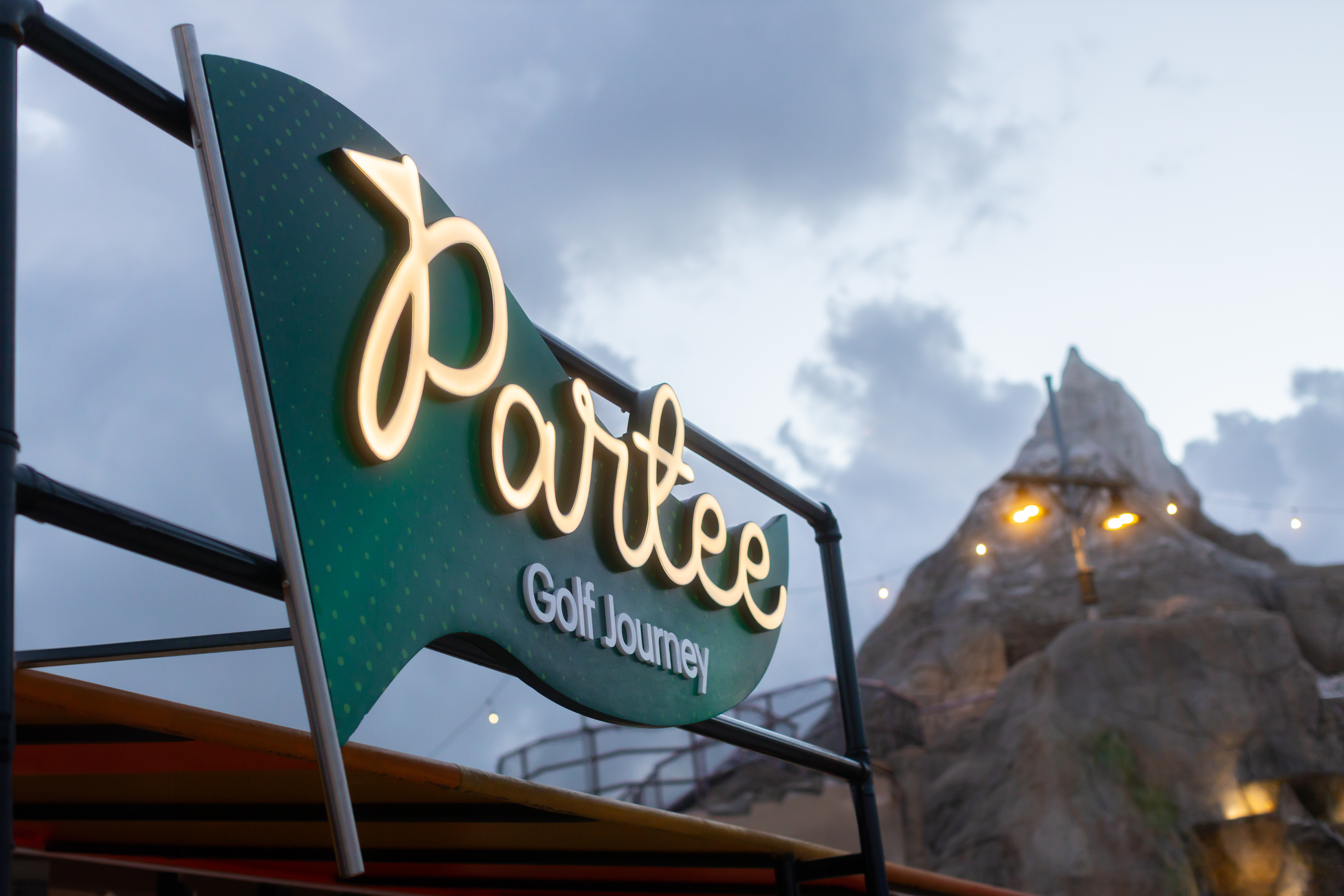 Partee Golf Journey illuminated sign with mountain golf course feature.