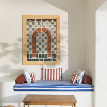 a bench with pillows and a table in a room with a picture on the wall