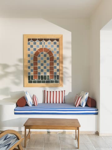 a bench with pillows and a table in a room with a picture on the wall