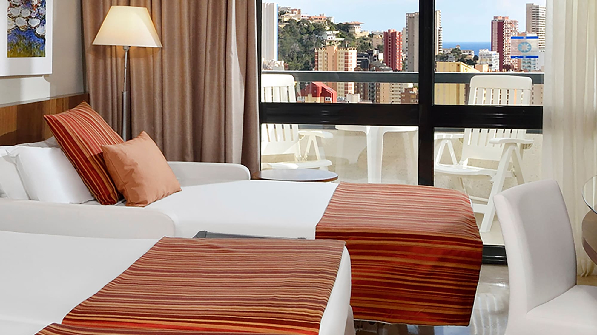 a room with two beds and a window with a view of the city