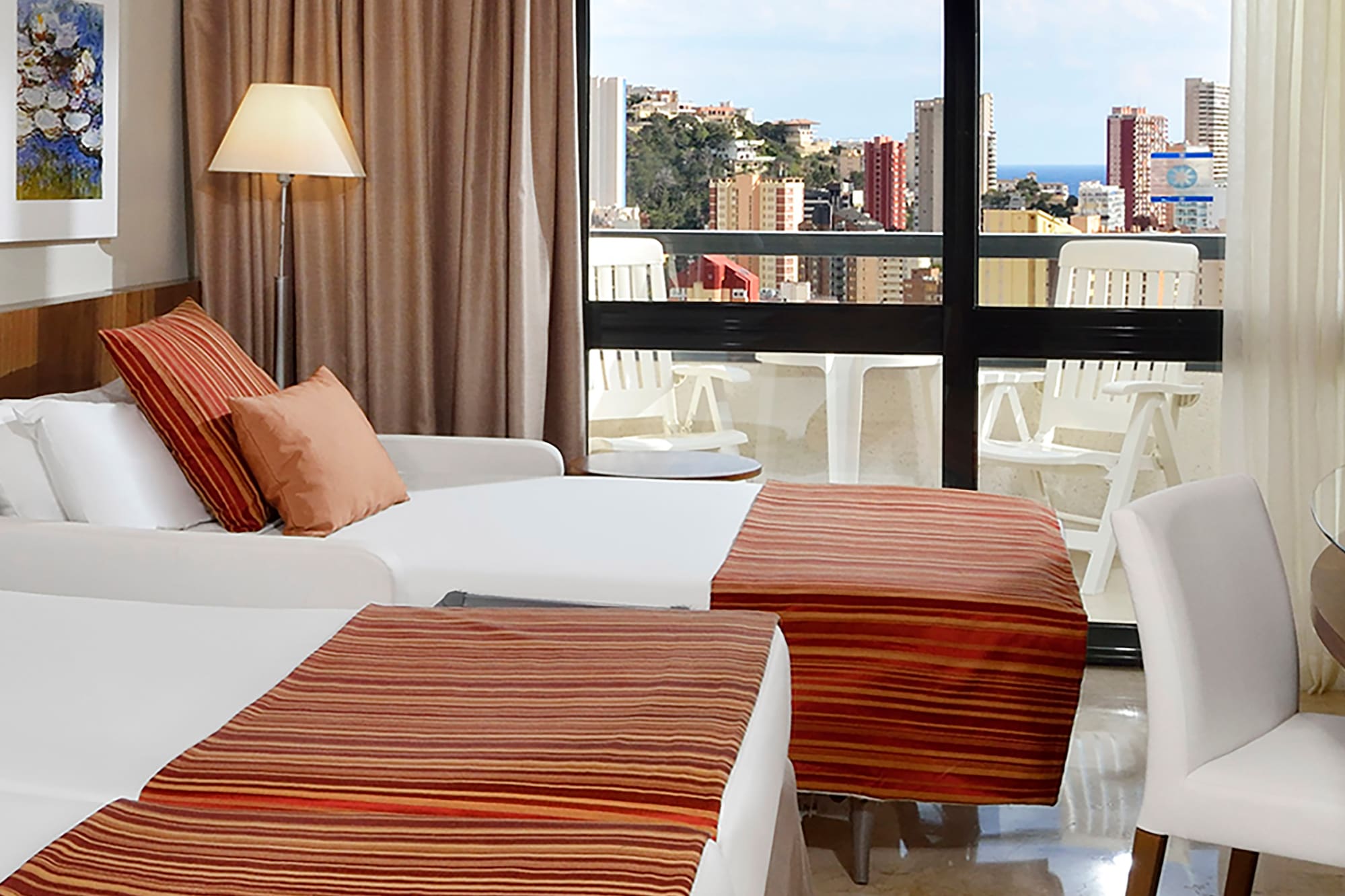 a room with two beds and a window with a view of the city