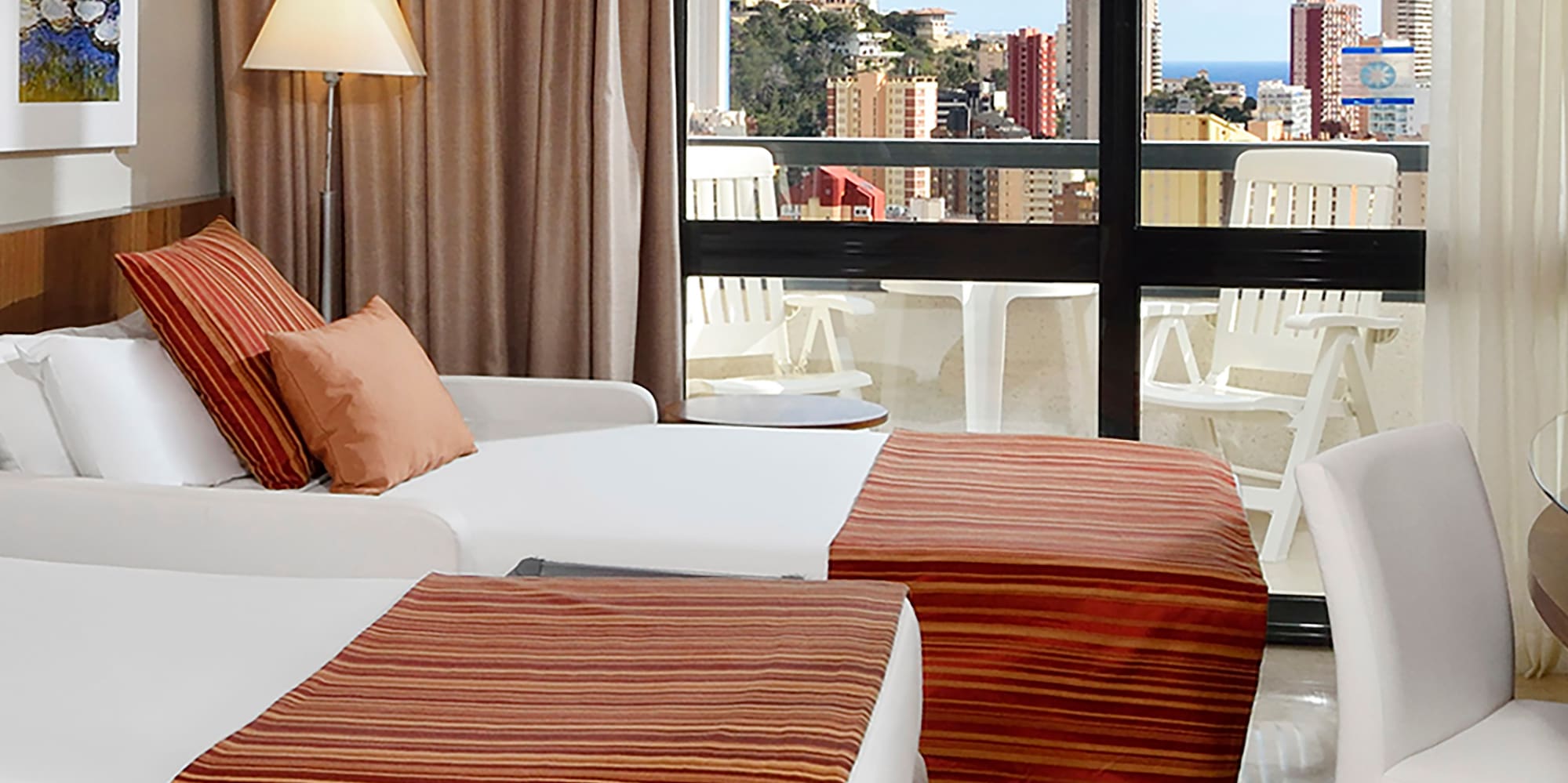 a room with two beds and a window with a view of the city