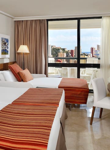 a room with two beds and a window with a view of the city