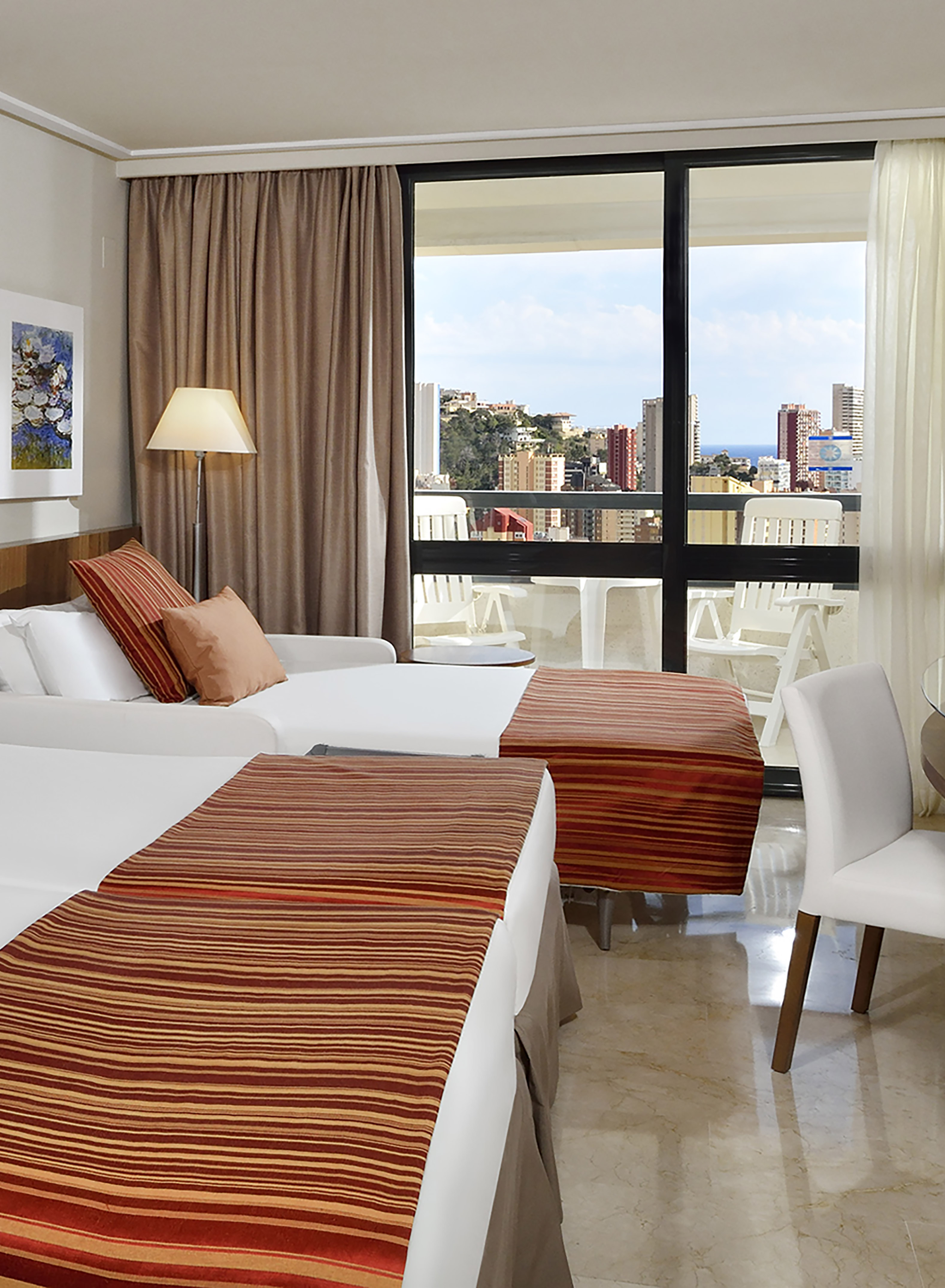 a room with two beds and a window with a view of the city