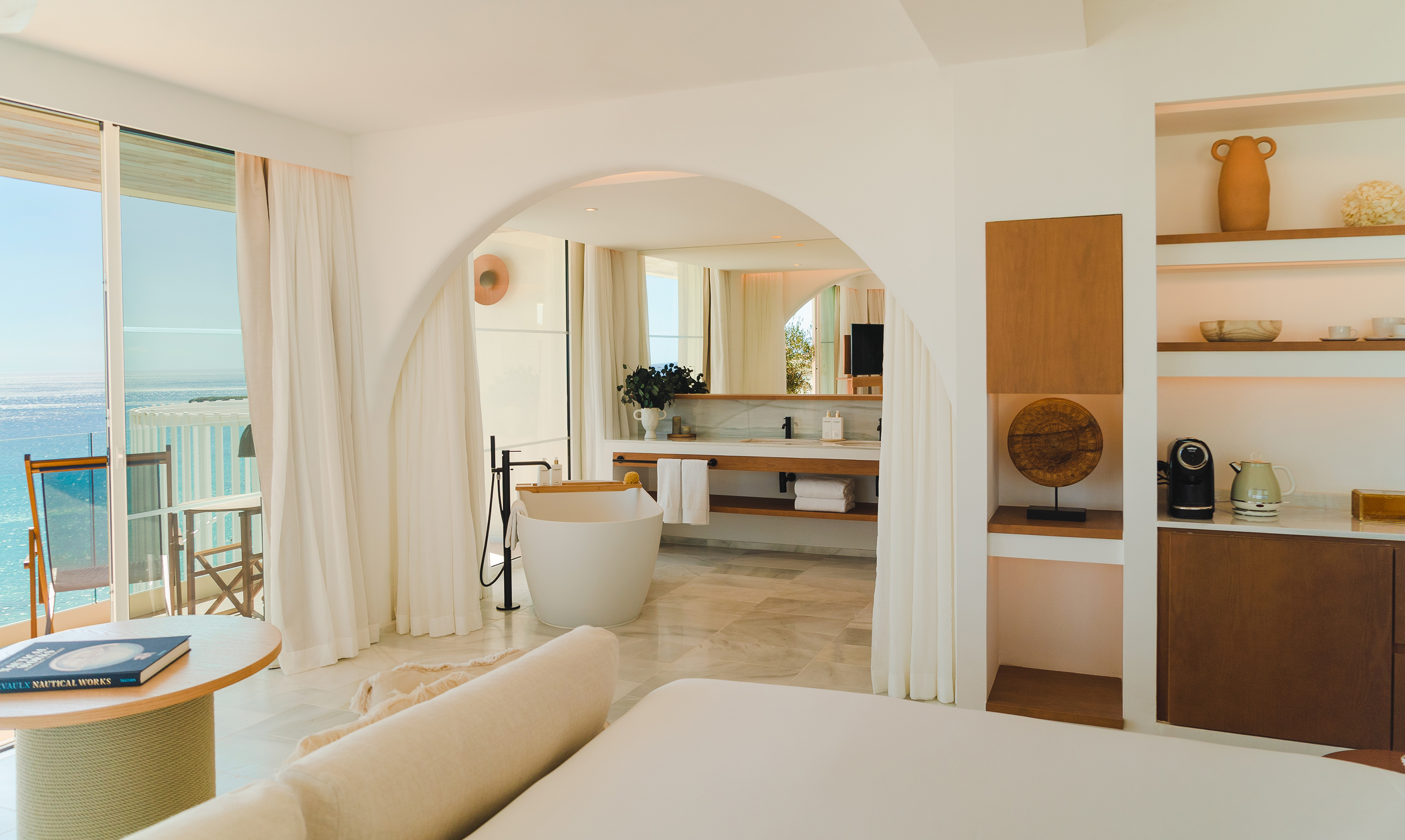 Luxury ocean view hotel room with freestanding tub and modern bathroom.