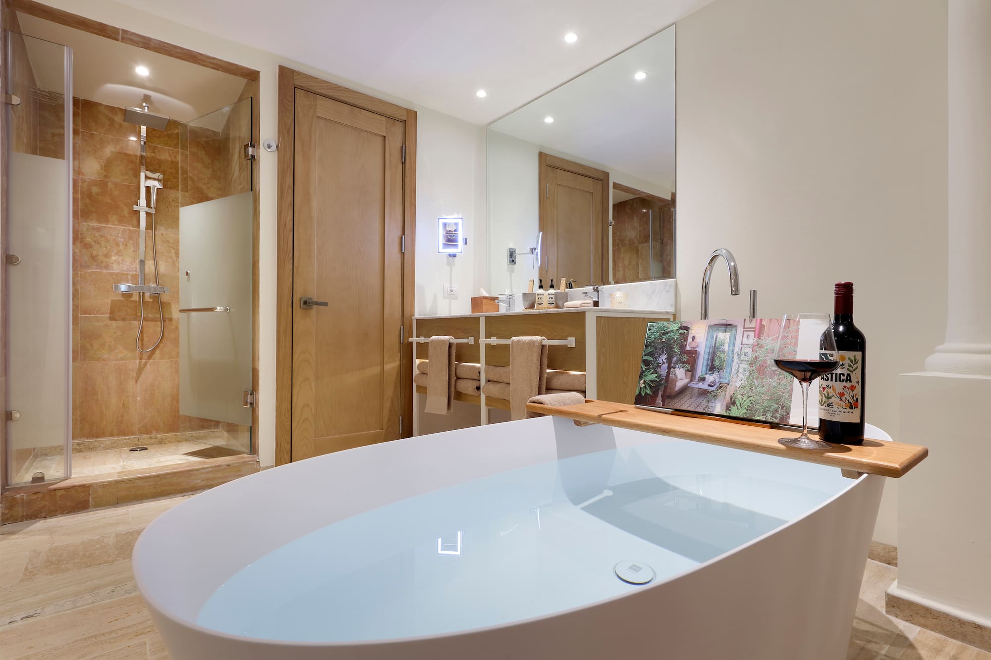 a bathroom with a tub and a glass of wine