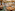 Jungle-themed restaurant with tree columns, wooden tables, green floor, and buffet.