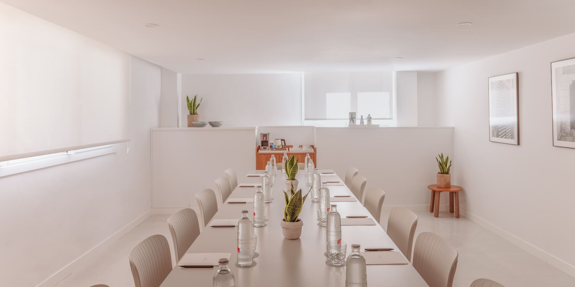 Espaciosa sala de reuniones moderna en tonos neutros con mesa larga y bebidas.