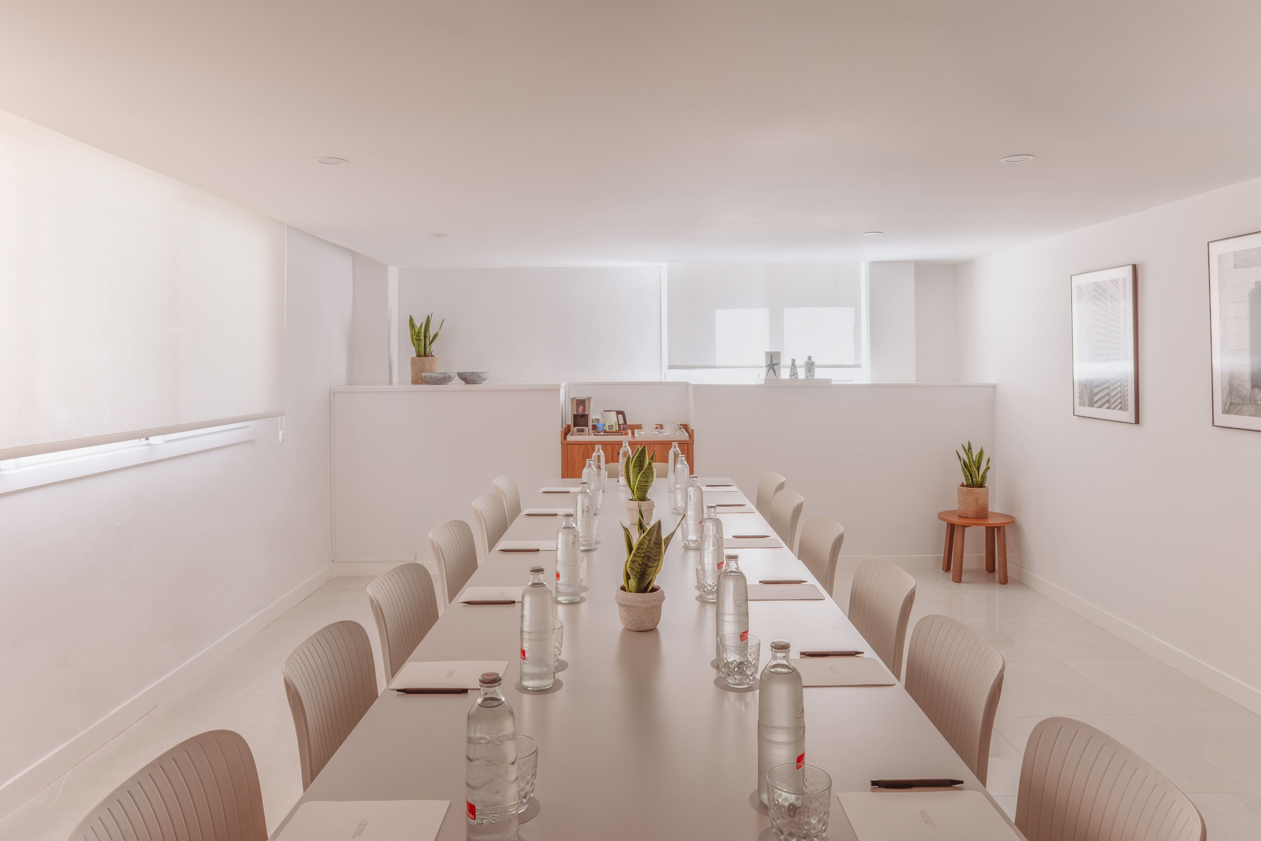 Espaciosa sala de reuniones moderna en tonos neutros con mesa larga y bebidas.