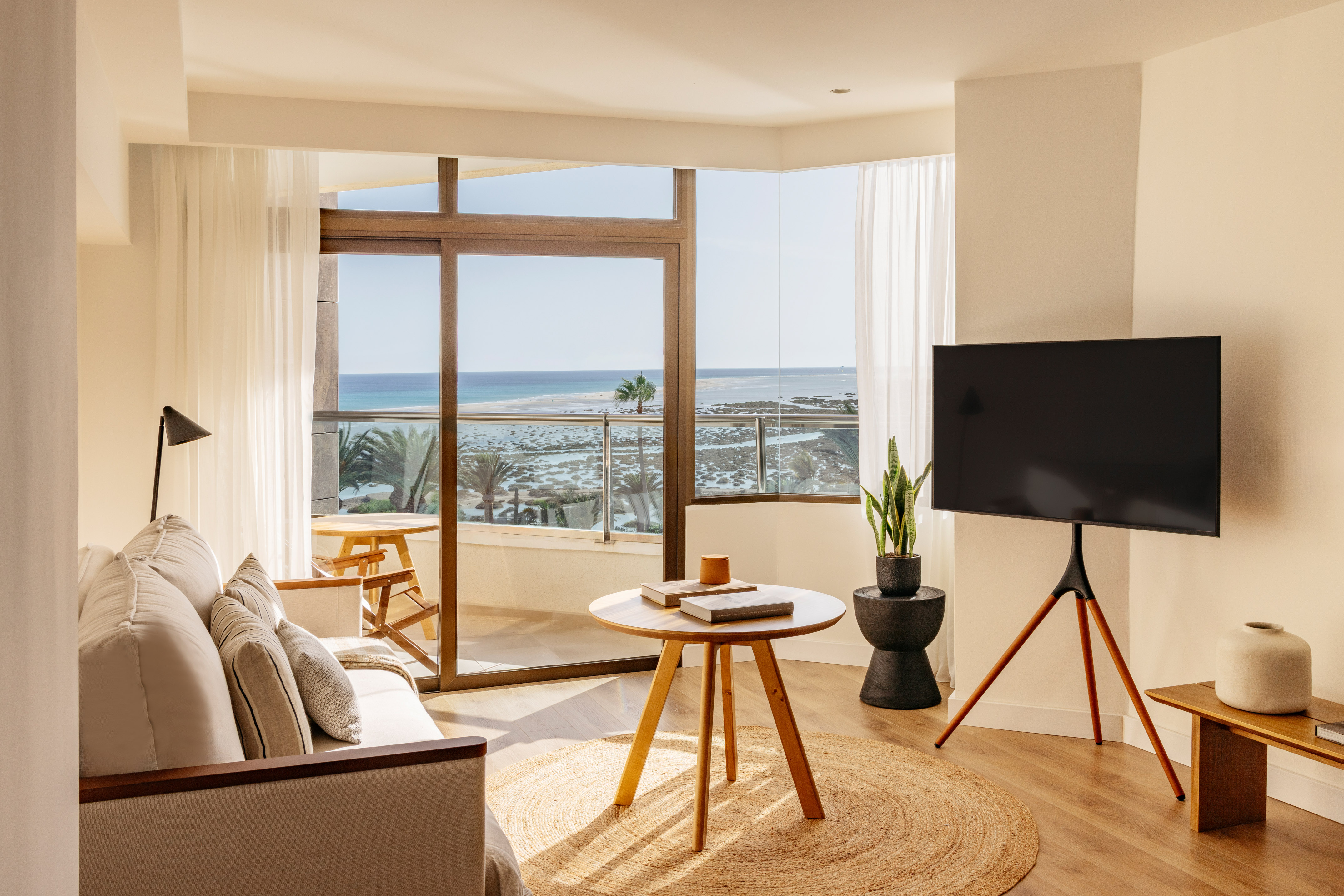Bright living room with ocean view balcony, modern decor, sofa, and TV.