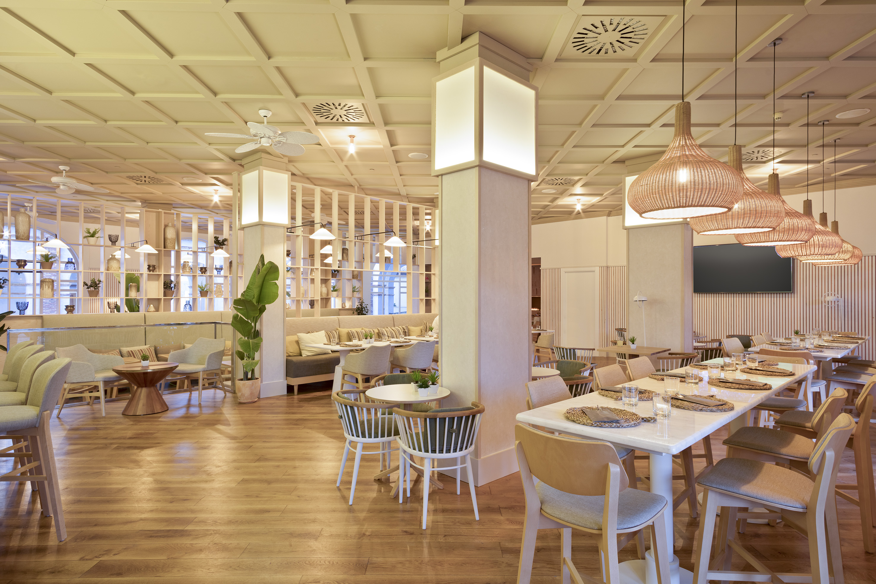 Bright modern restaurant interior featuring wood floors and rattan lights.