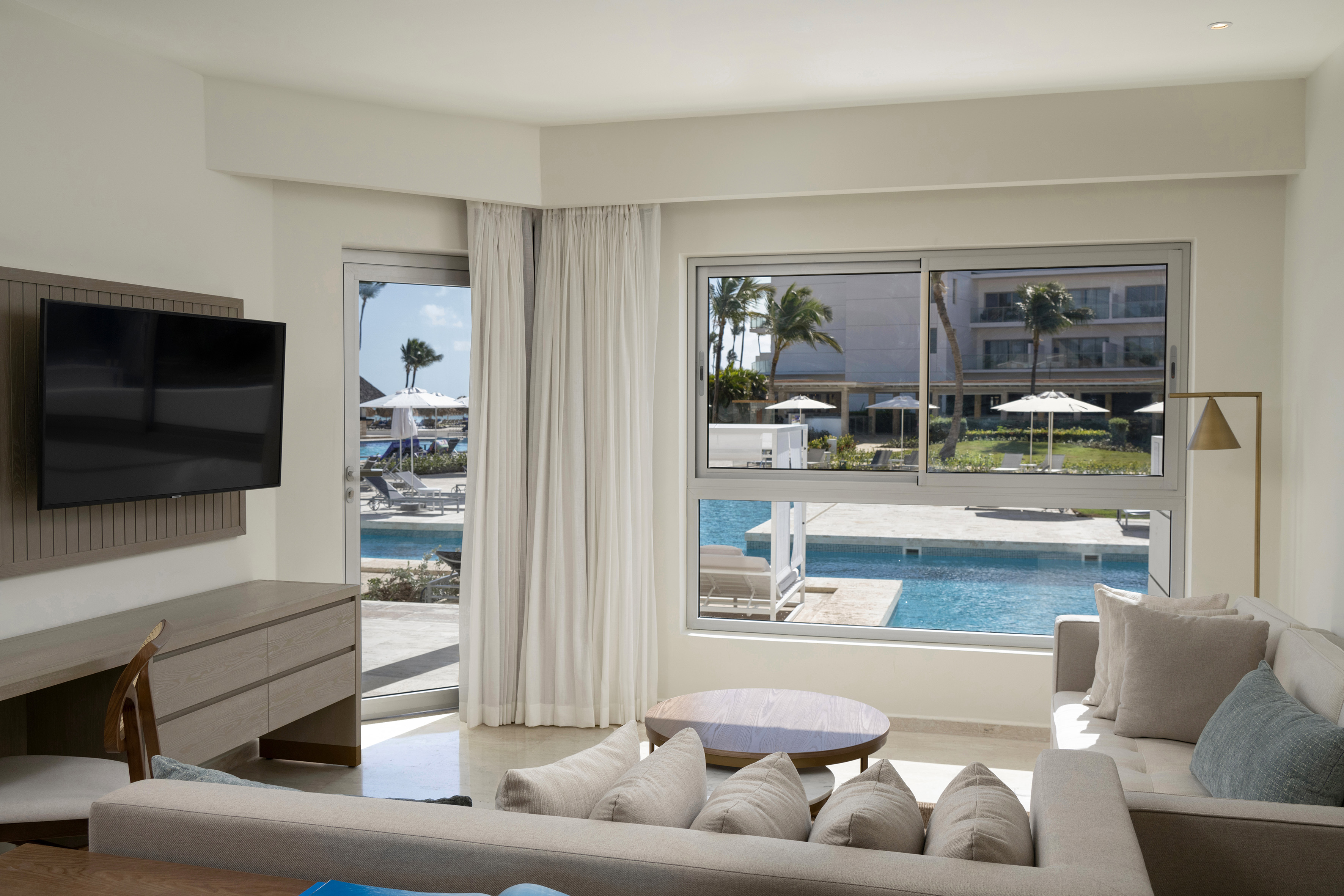 Modern resort suite living area with pool view and palm trees.