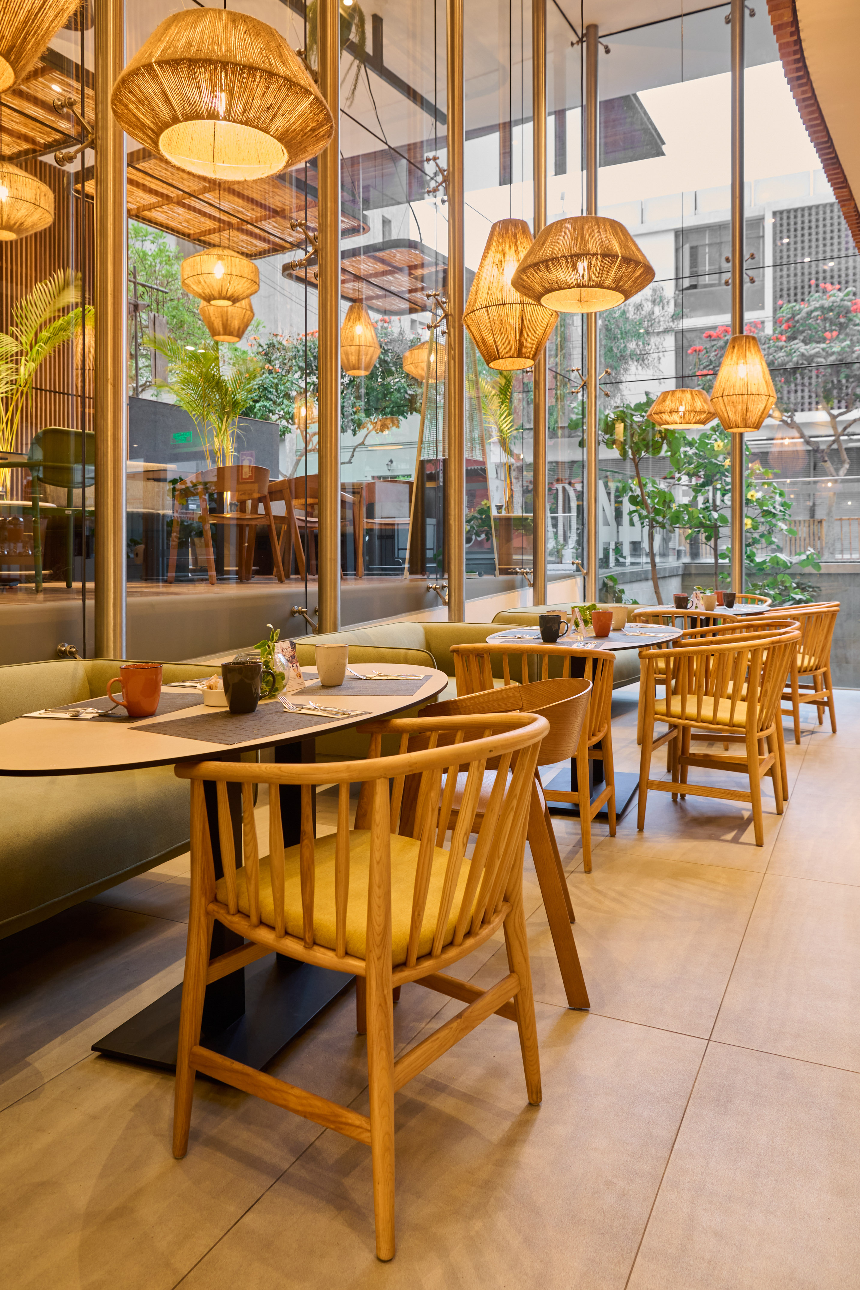 Modern cafe with wood chairs, green booth seating, and woven pendant lights.