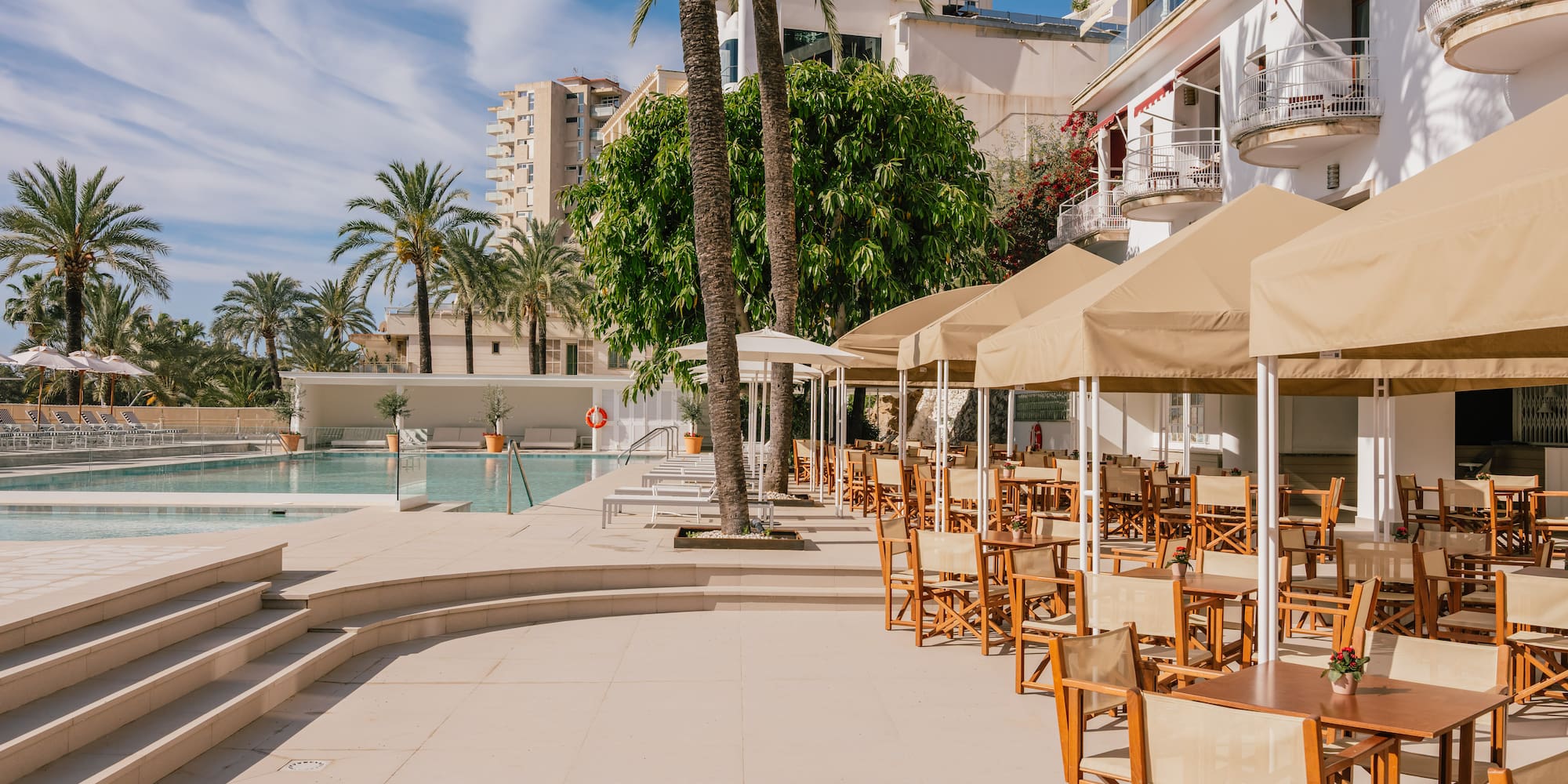 a pool with tables and chairs and umbrellas