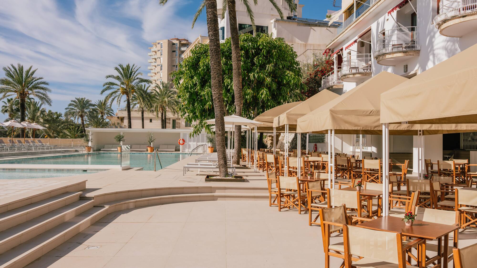 a pool with tables and chairs and umbrellas