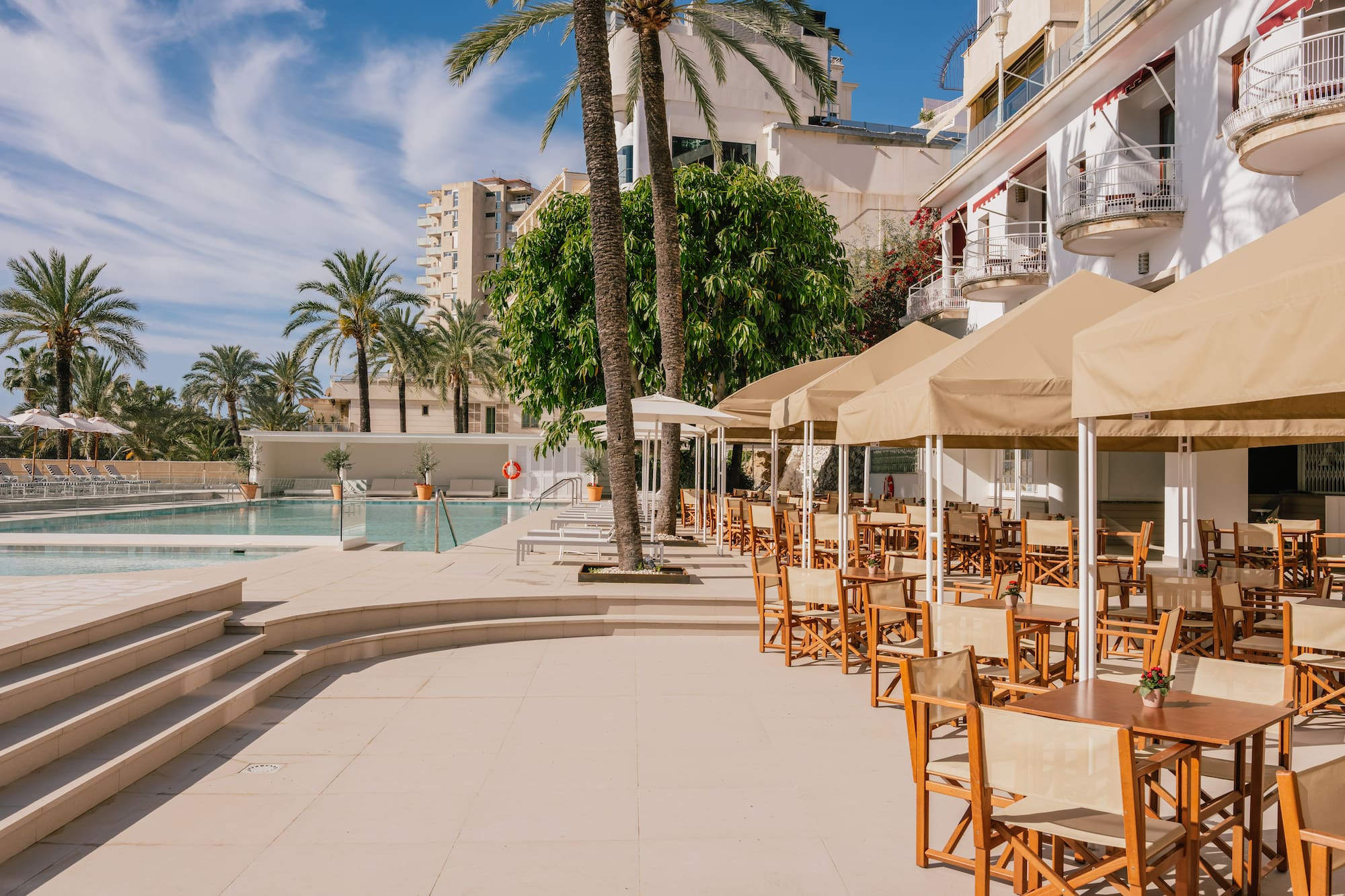 a pool with tables and chairs and umbrellas