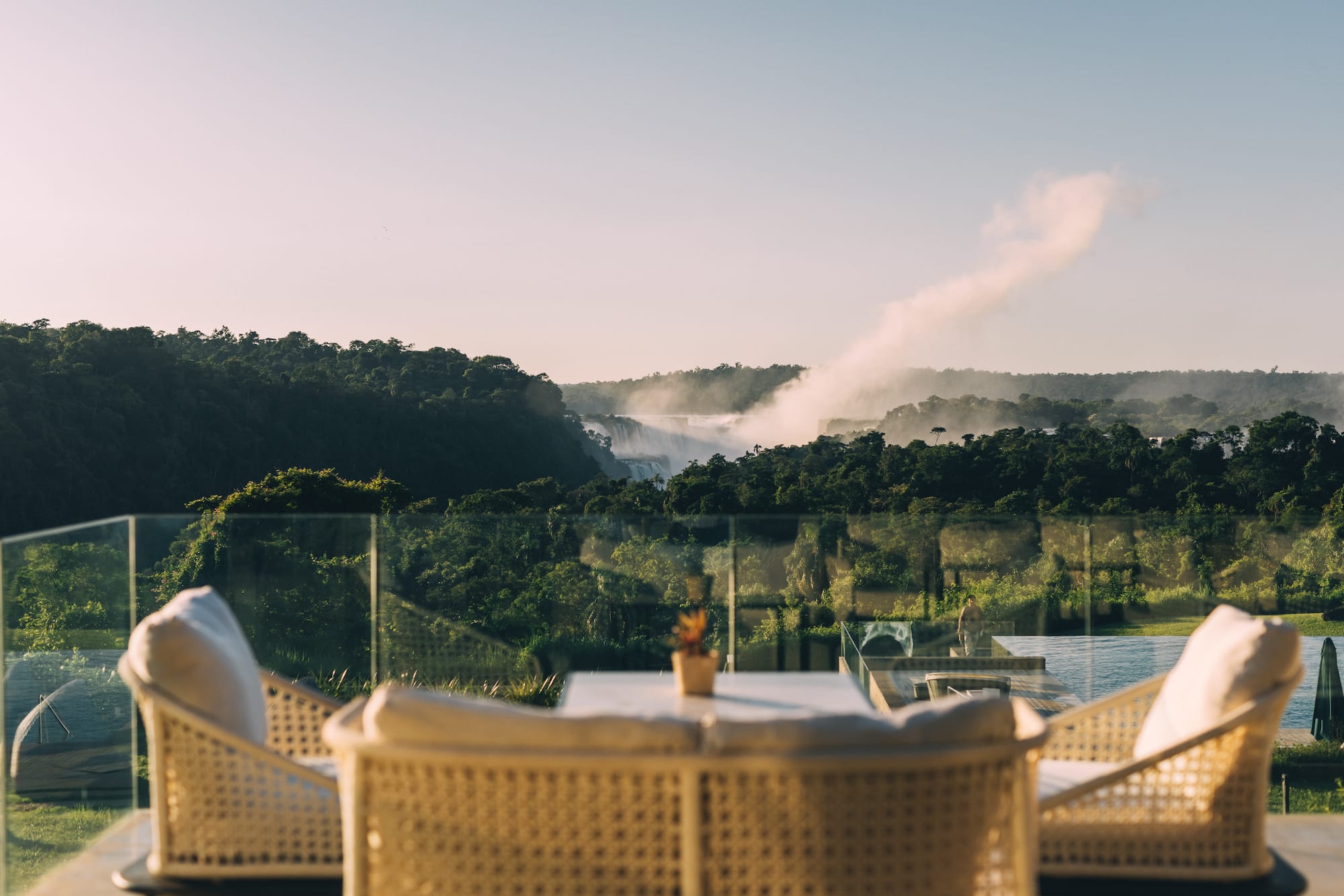 Patio with wicker chairs facing the misty Iguazu Falls and rainforest.