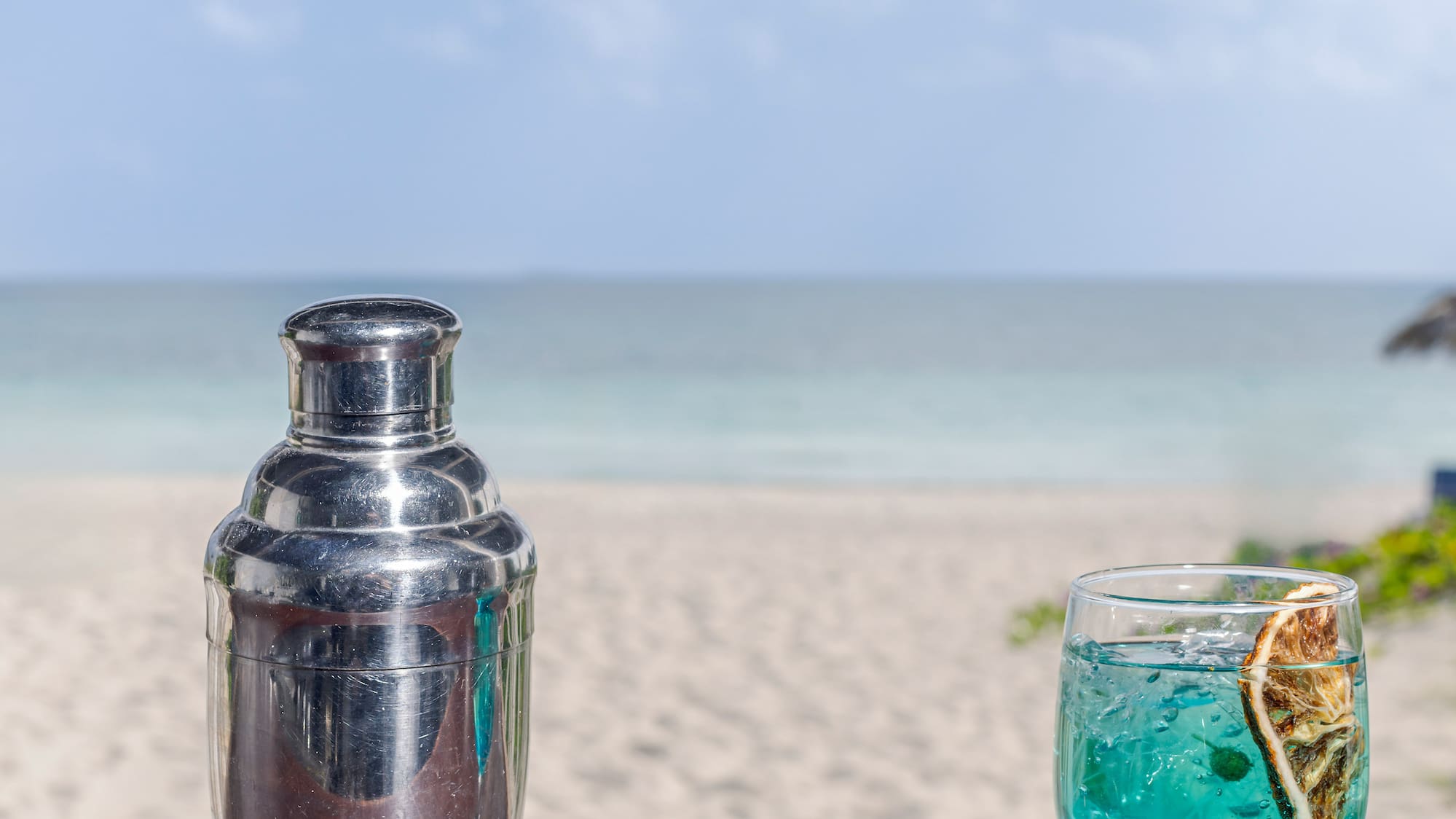 a cocktail shaker and a glass of blue liquid on a table