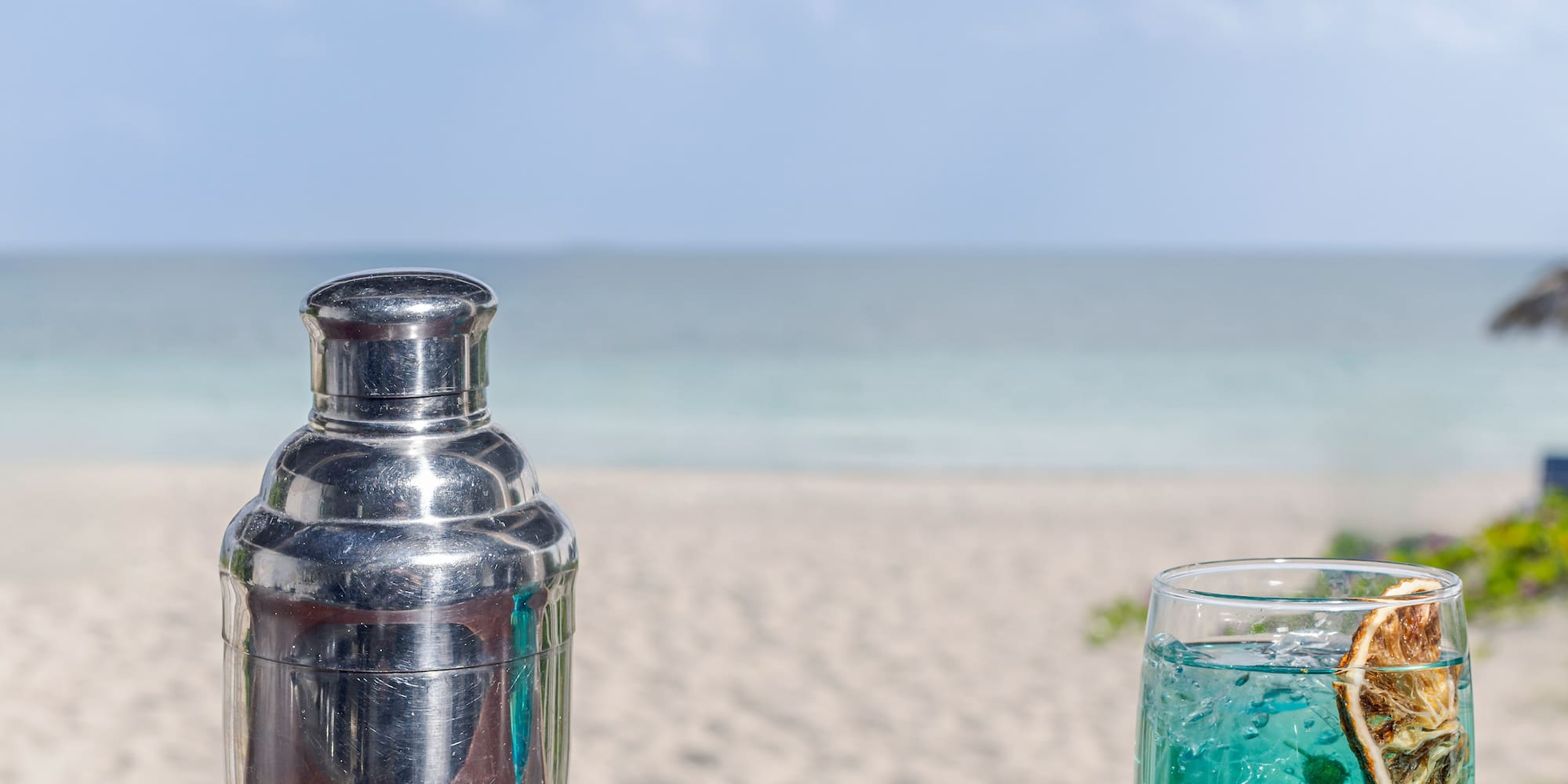 a cocktail shaker and a glass of blue liquid on a table