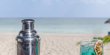 a cocktail shaker and a glass of blue liquid on a table
