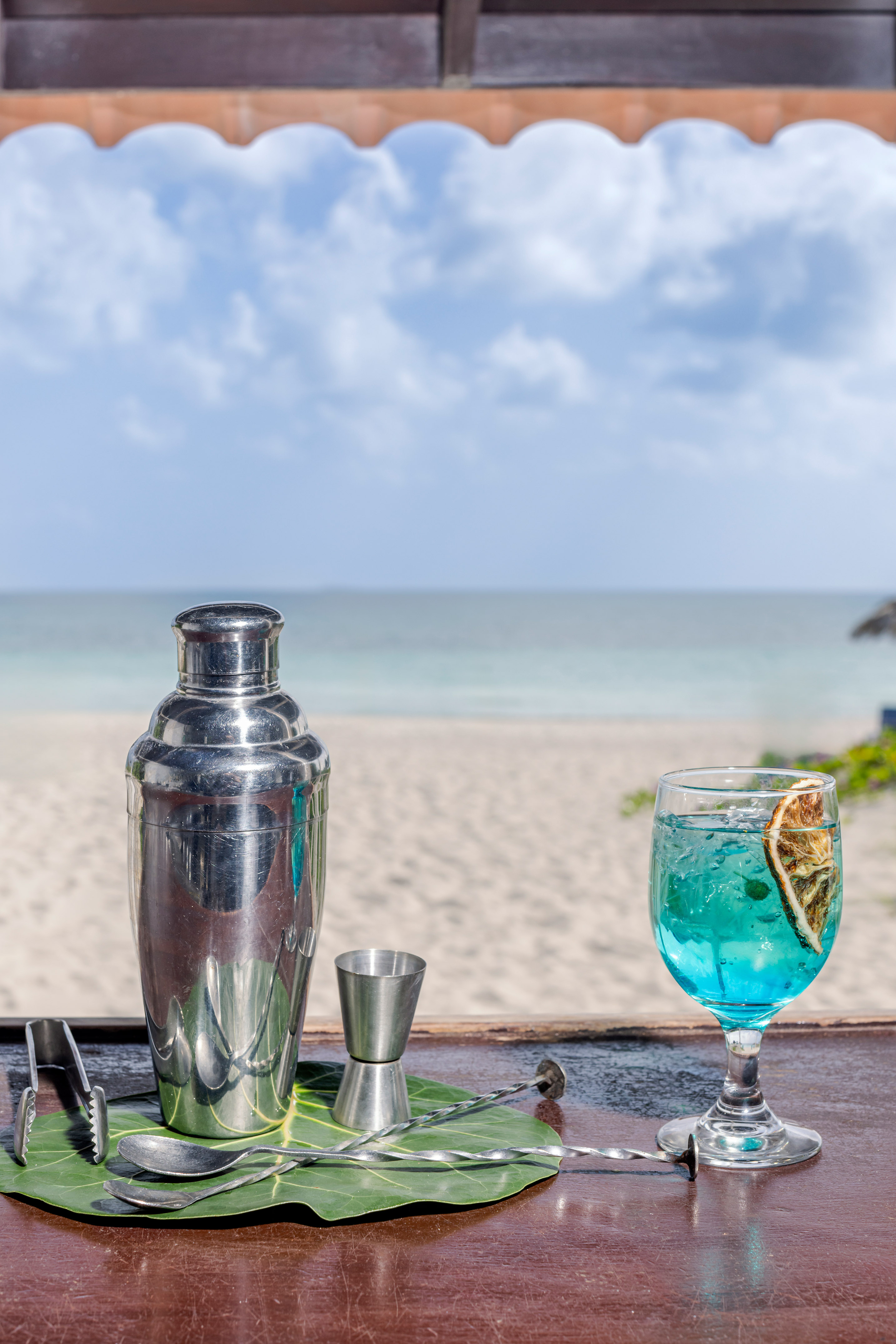 a cocktail shaker and a glass of blue liquid on a table