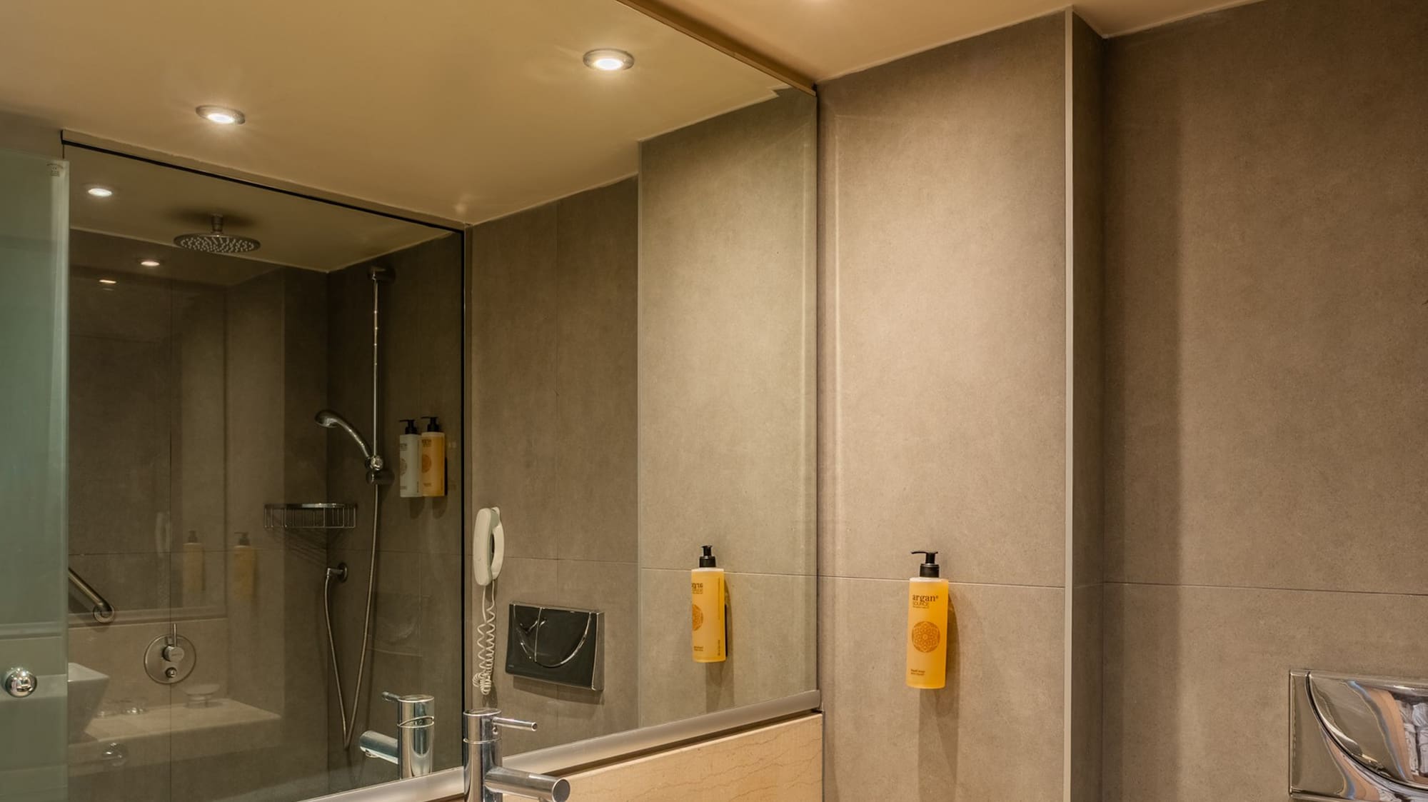 Modern hotel bathroom vanity with sink, marble counter, shower, and toilet.