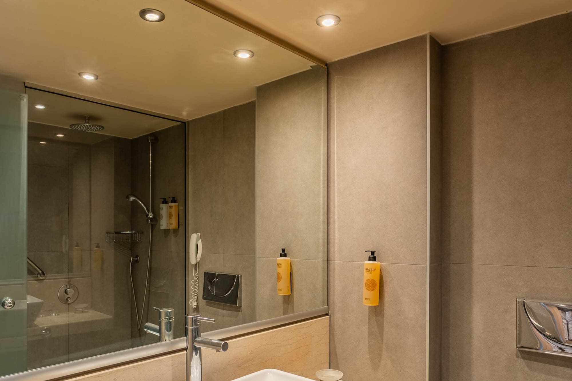 Modern hotel bathroom vanity with sink, marble counter, shower, and toilet.