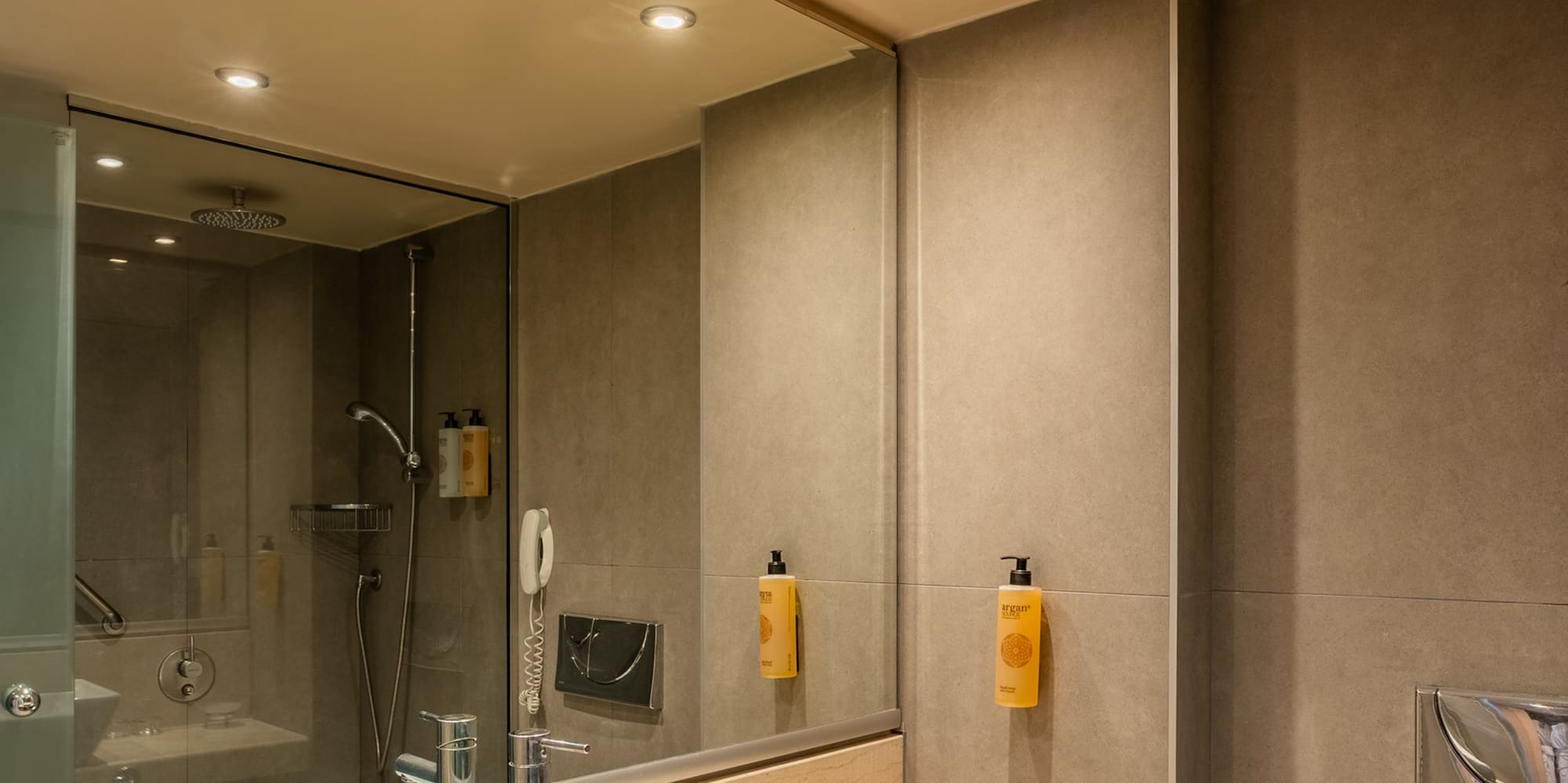 Modern hotel bathroom vanity with sink, marble counter, shower, and toilet.