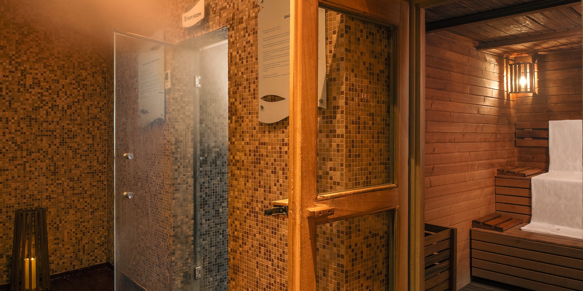 Spa steam room with mosaic tiles next to open wooden sauna.