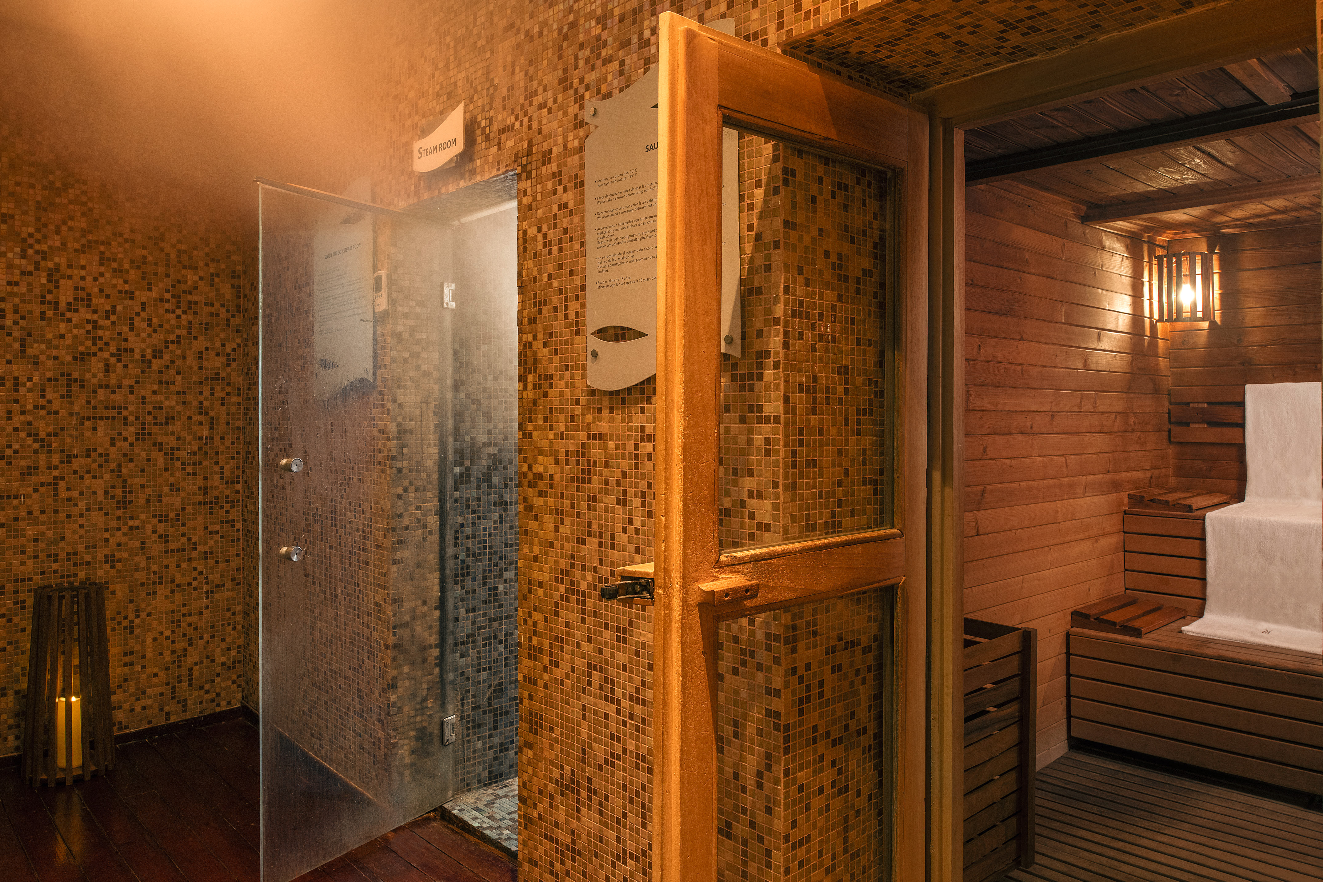 Spa steam room with mosaic tiles next to open wooden sauna.
