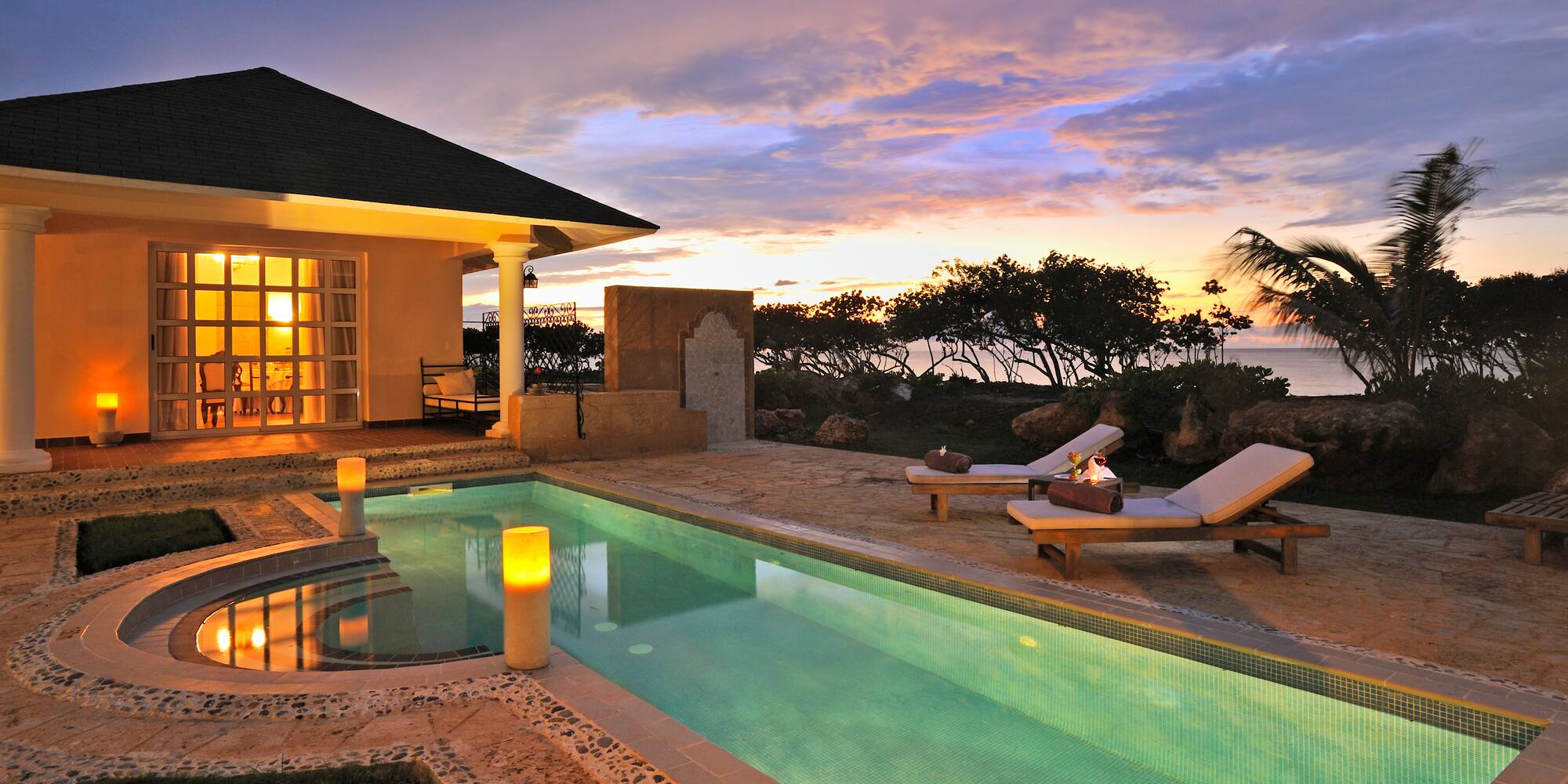 a pool with a house and a building with a sunset