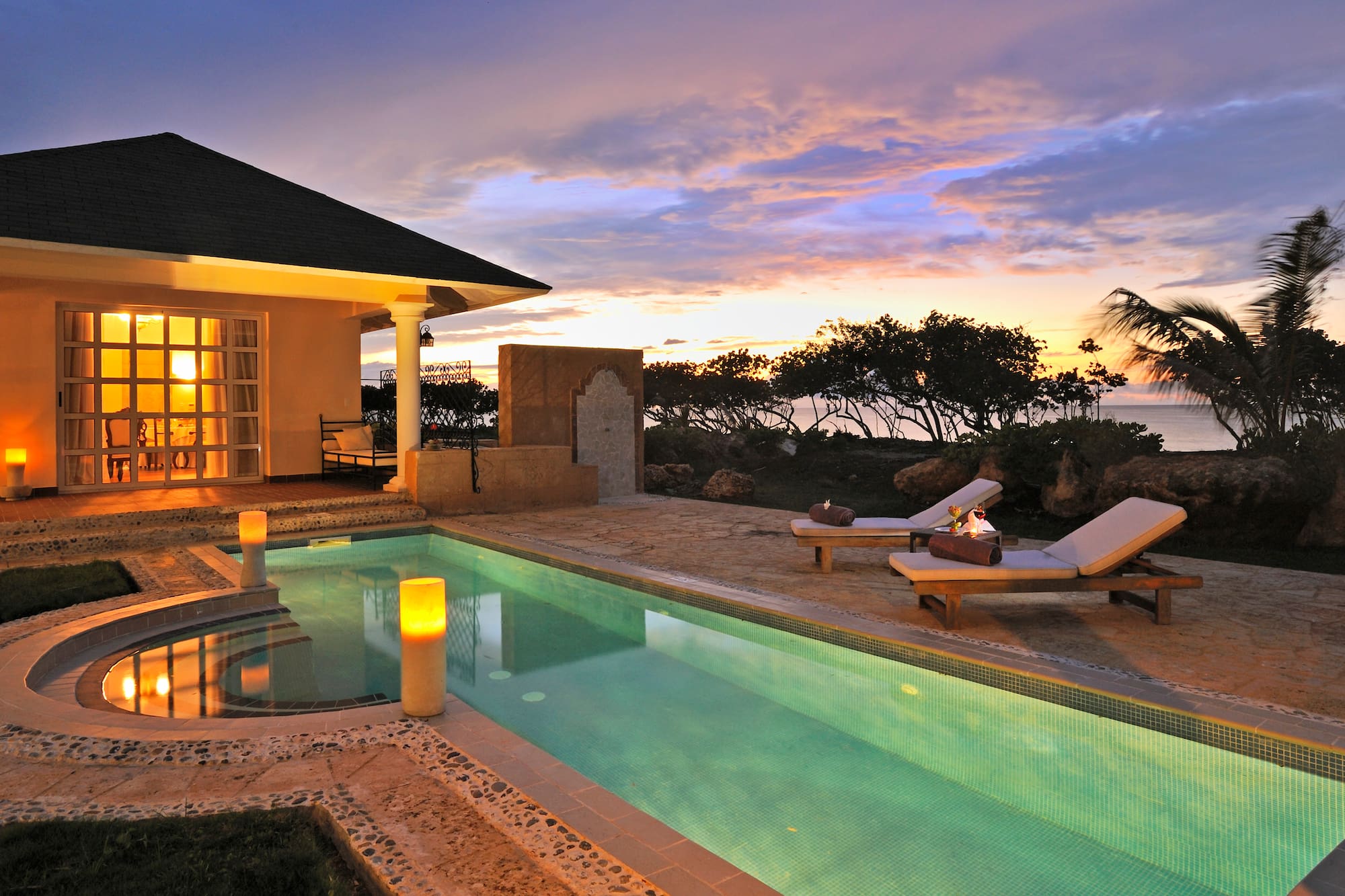 a pool with a house and a building with a sunset