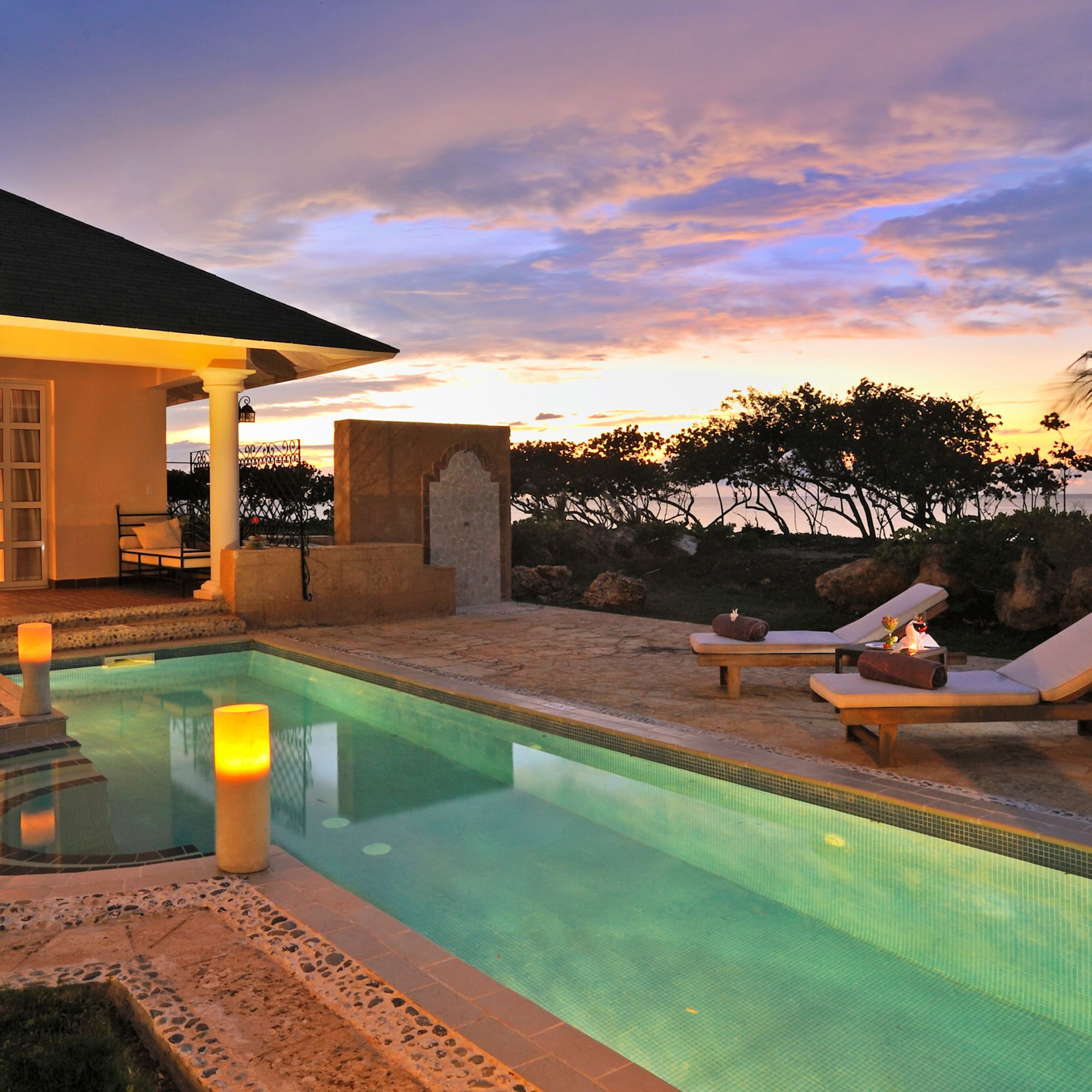 a pool with a house and a building with a sunset