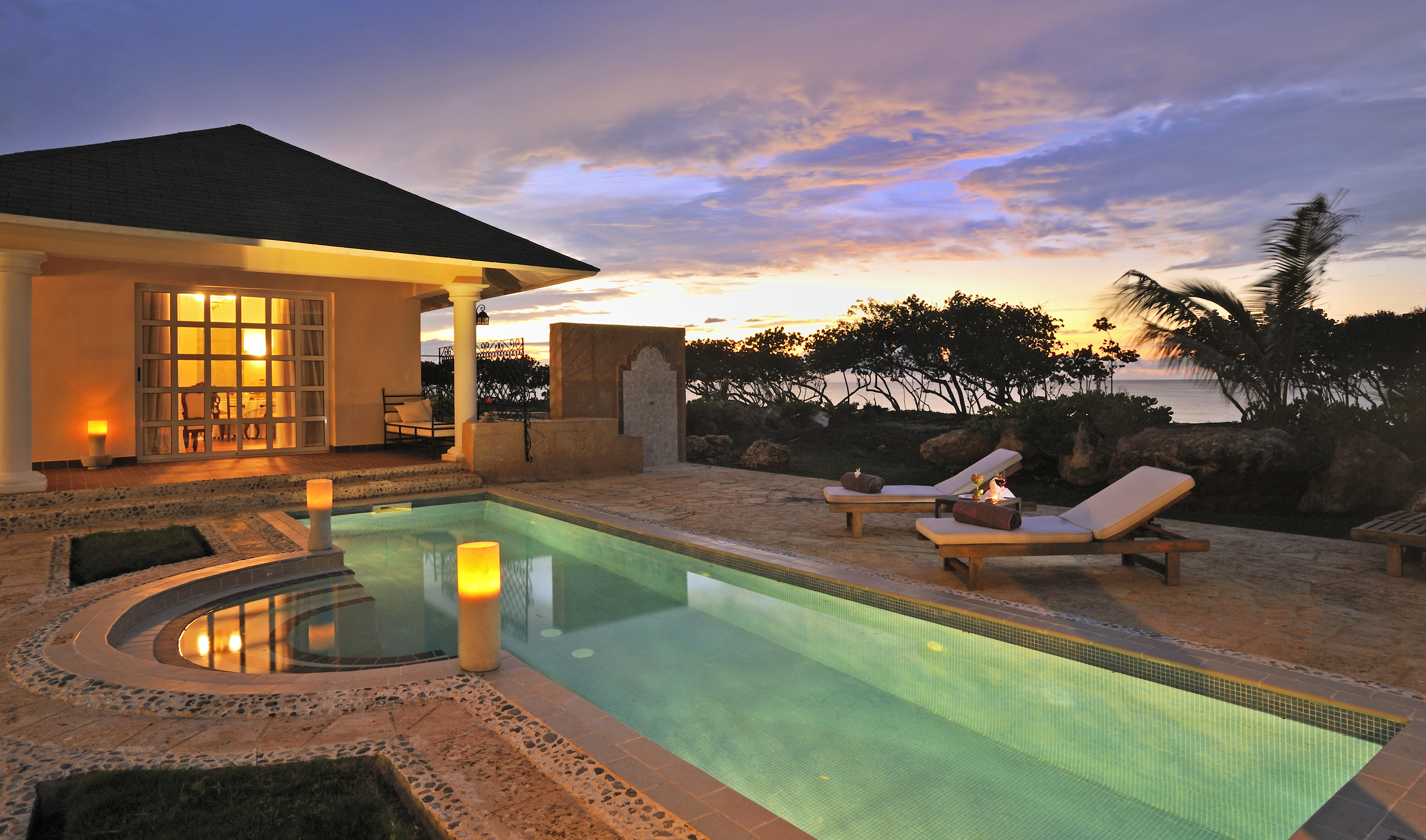a pool with a house and a building with a sunset