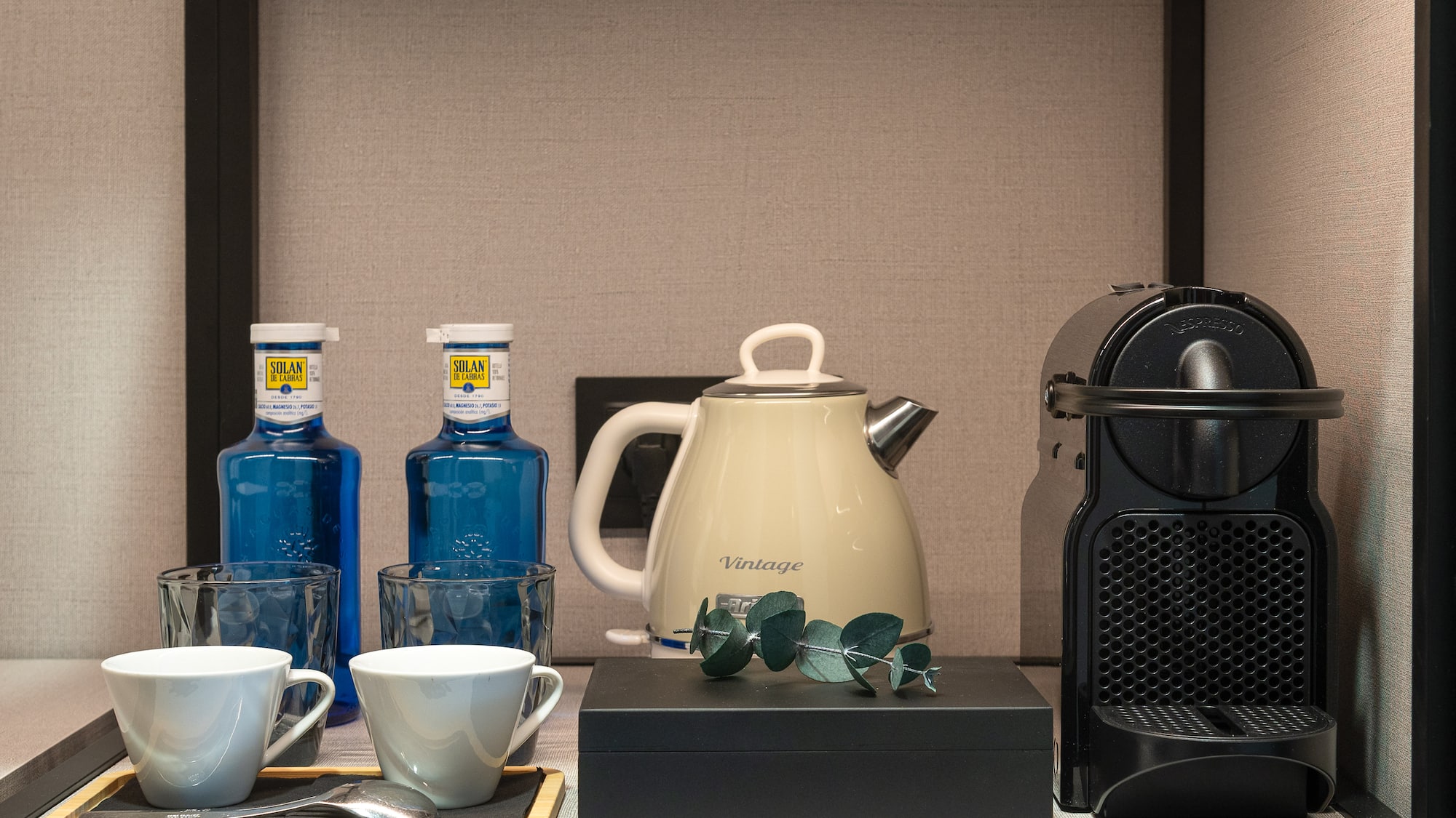 Hotel room amenities: Nespresso, electric kettle, Solan de Cabras water, cups.