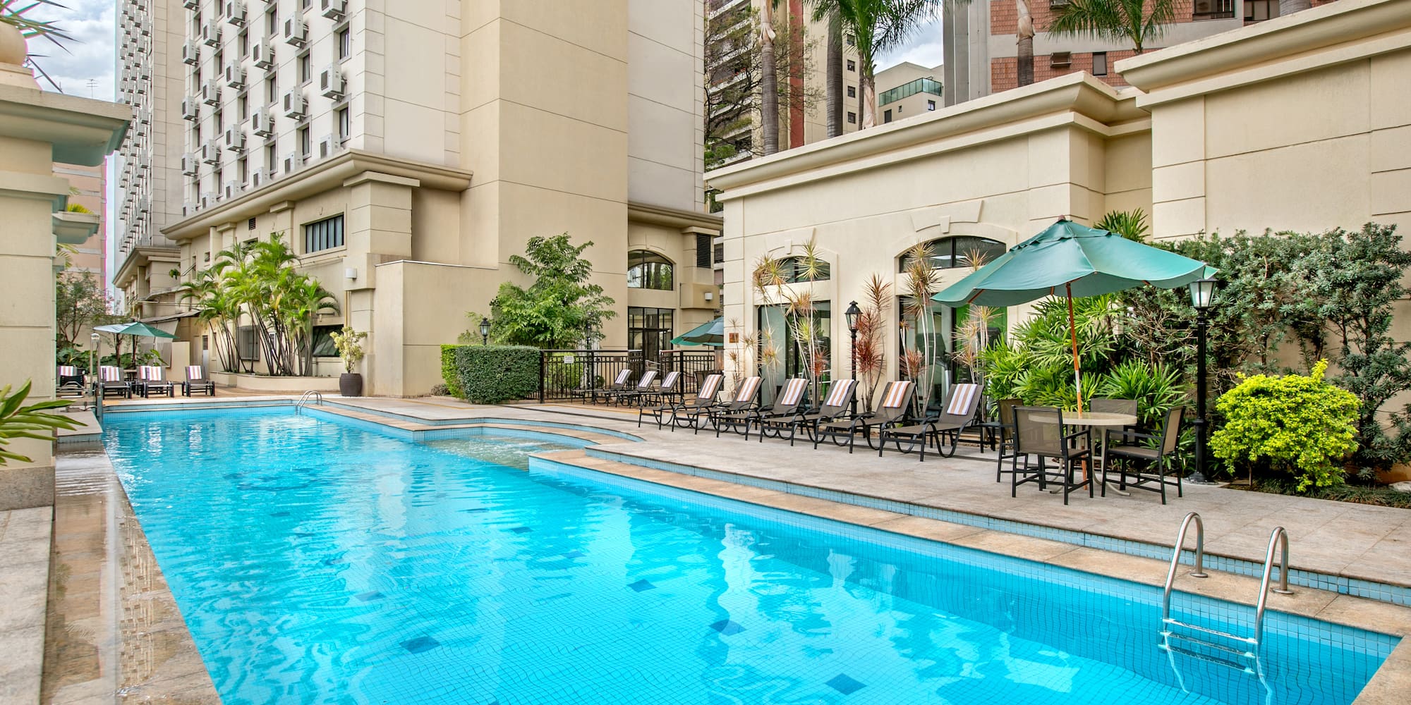a pool with chairs and umbrellas in front of a building