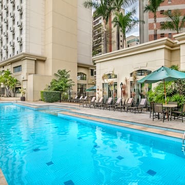 a pool with chairs and umbrellas in front of a building