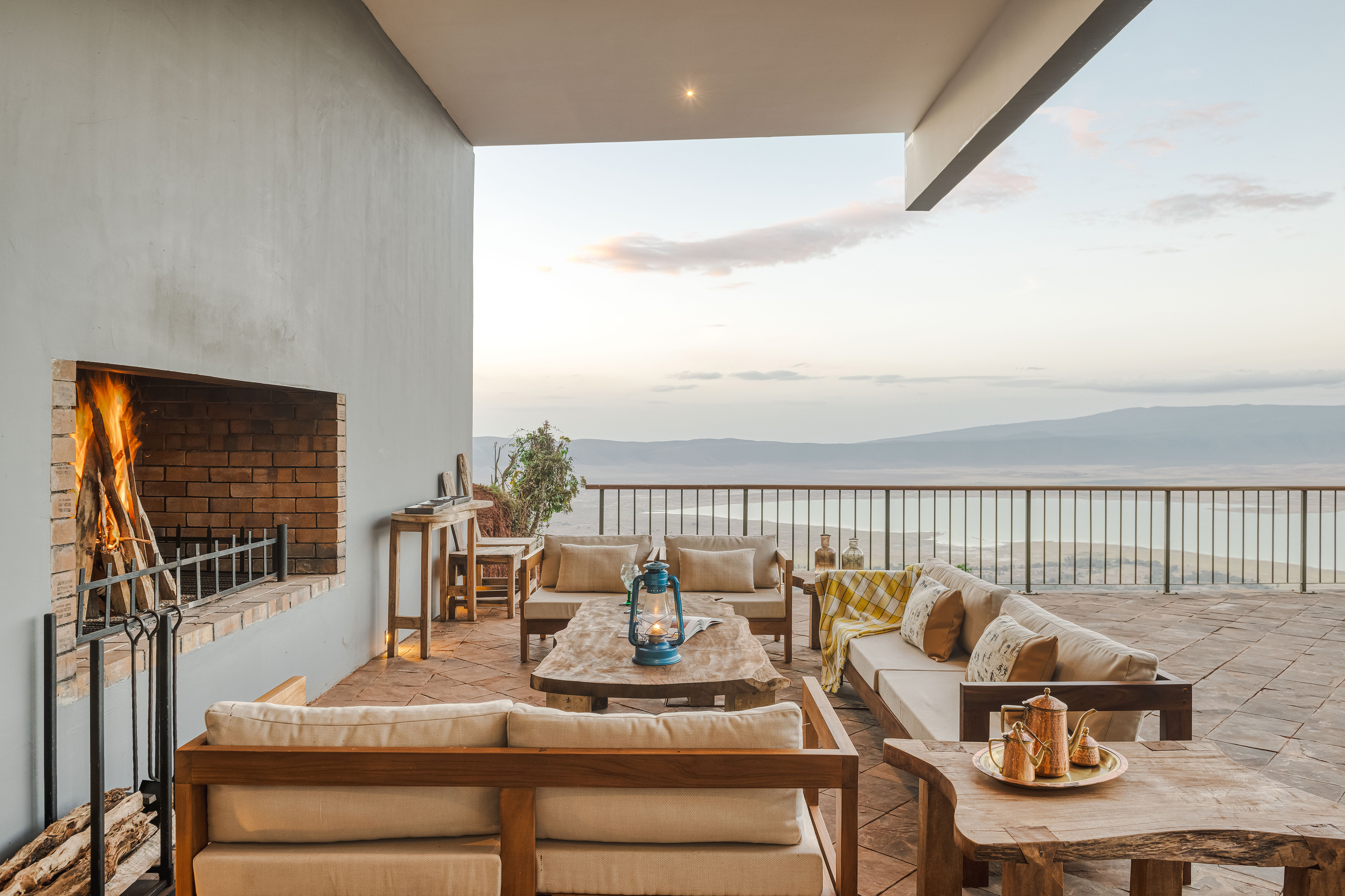 Outdoor patio with lit fireplace, comfortable sofas, and panoramic lake view.