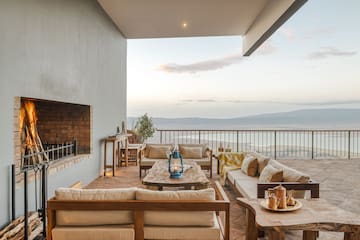 a patio with a view of the ocean and a fireplace