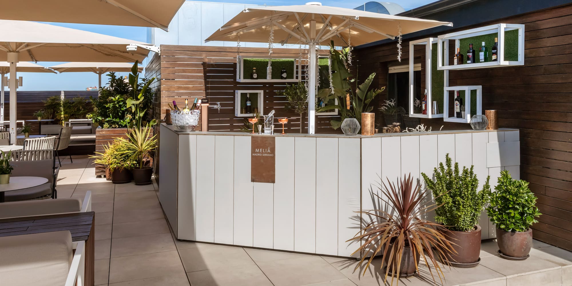 Meliã Madrid Serrano outdoor rooftop bar with drinks, plants, and shaded seating.