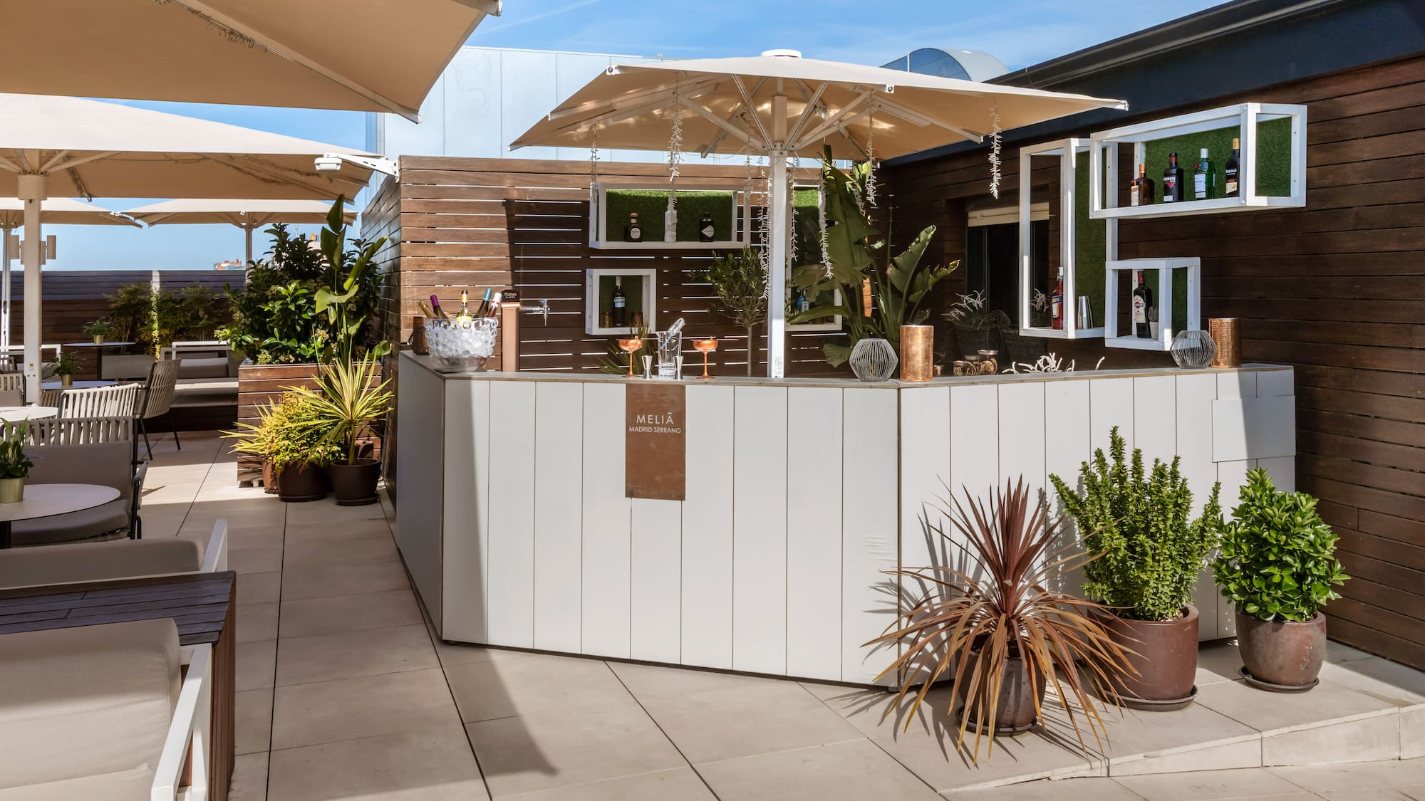 Meliã Madrid Serrano outdoor rooftop bar with drinks, plants, and shaded seating.