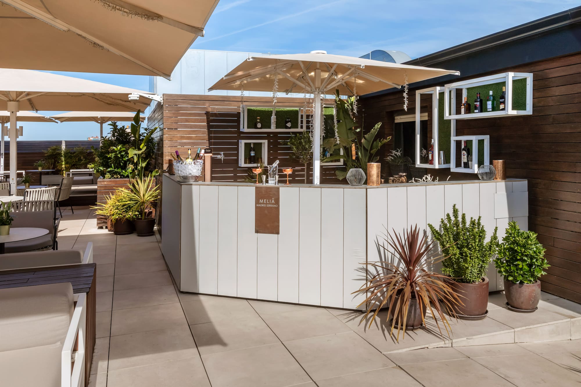 Meliã Madrid Serrano outdoor rooftop bar with drinks, plants, and shaded seating.