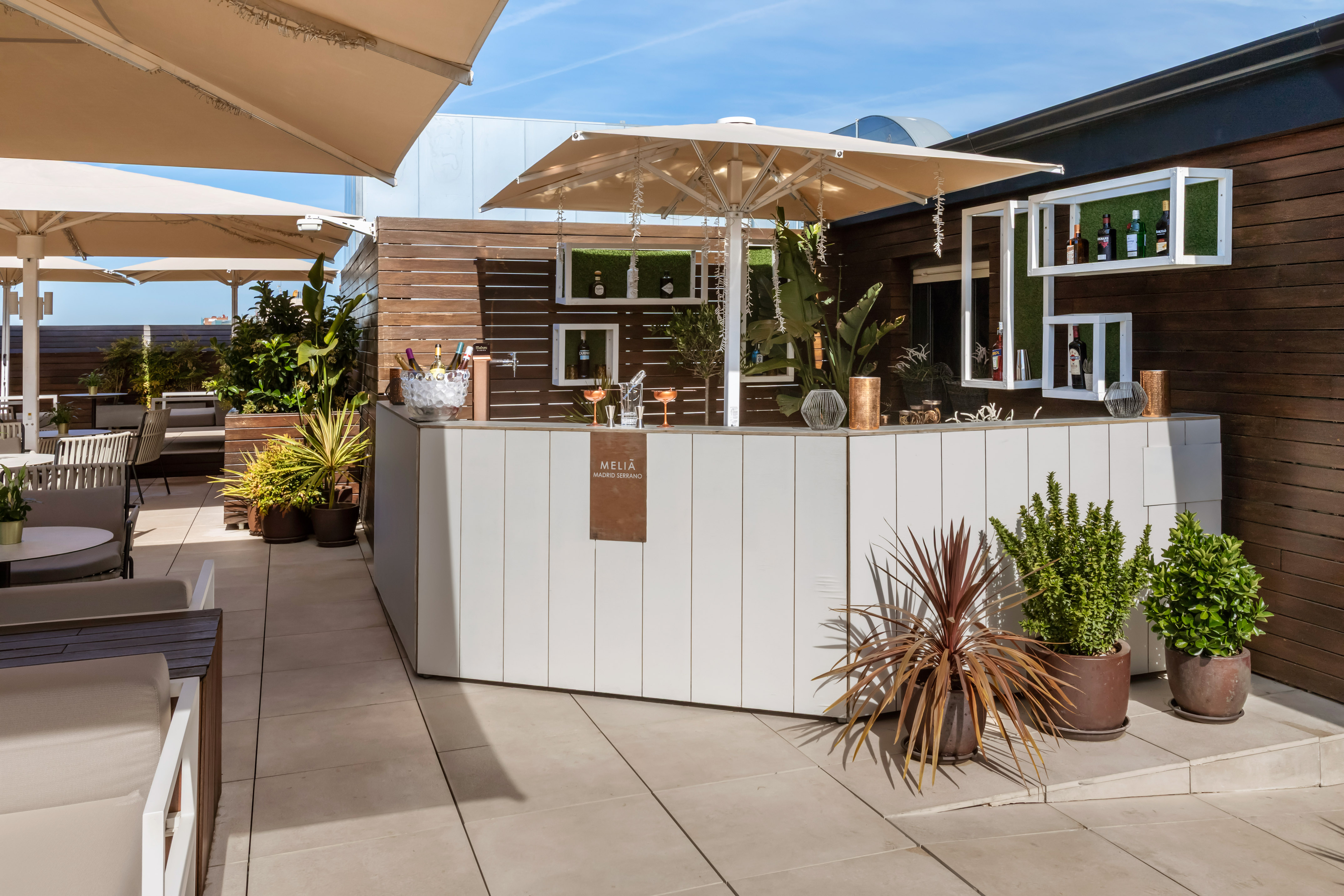 Meliã Madrid Serrano outdoor rooftop bar with drinks, plants, and shaded seating.