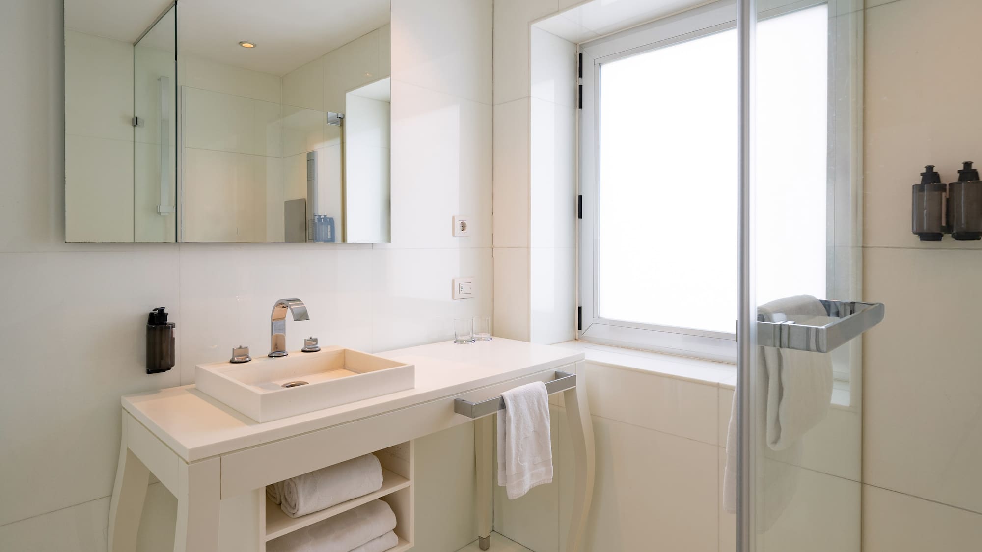 Modern white bathroom with vanity, vessel sink, mirror, and glass shower.
