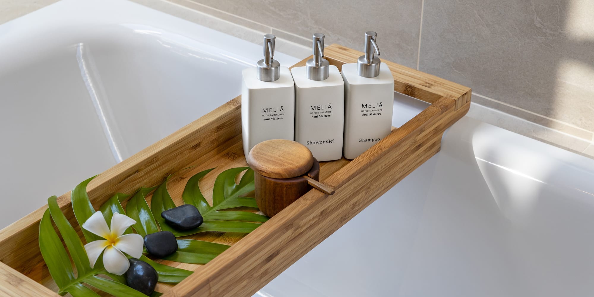 a tray of white bottles and green leaves on a bathtub