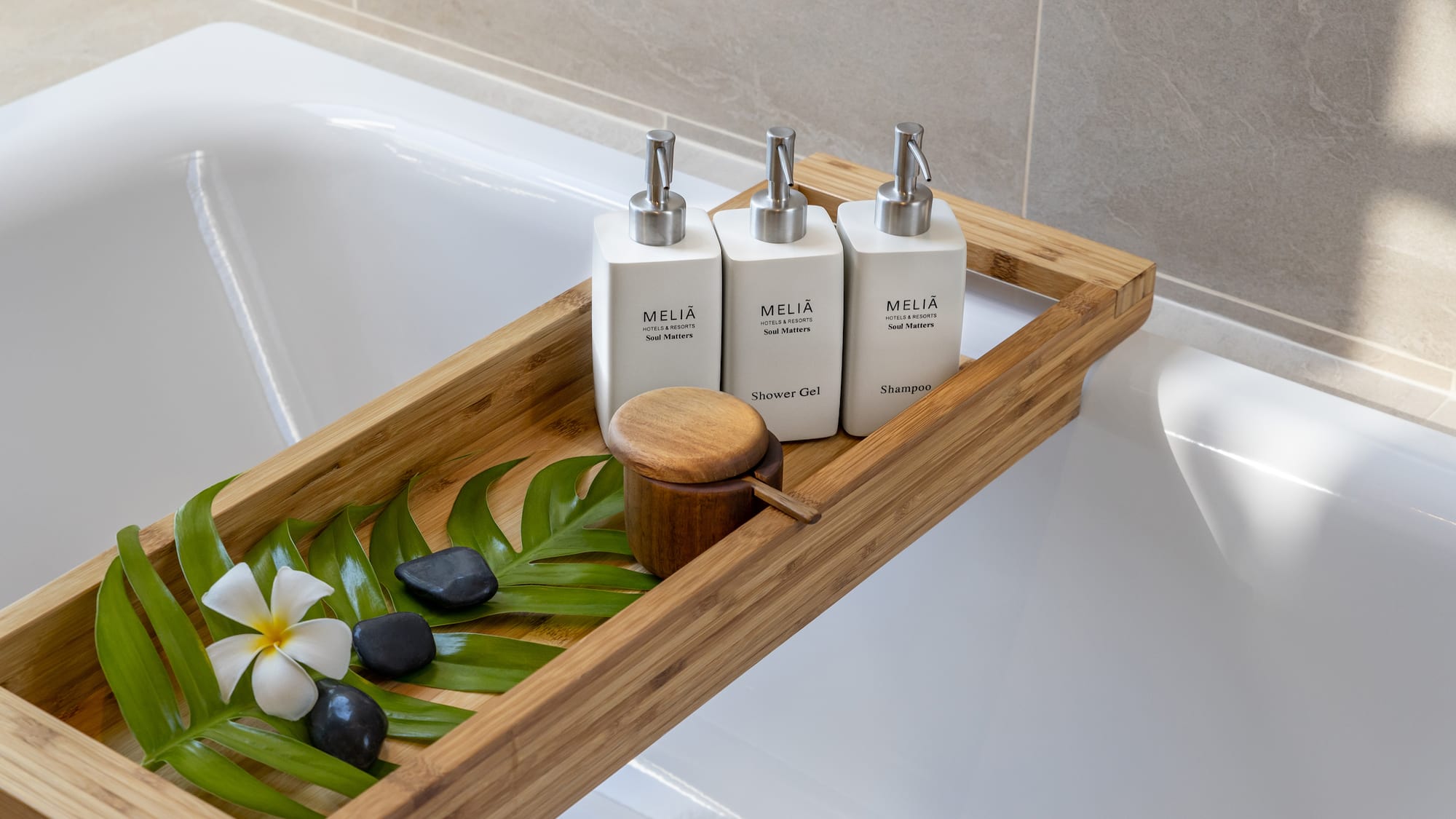 a tray of white bottles and green leaves on a bathtub