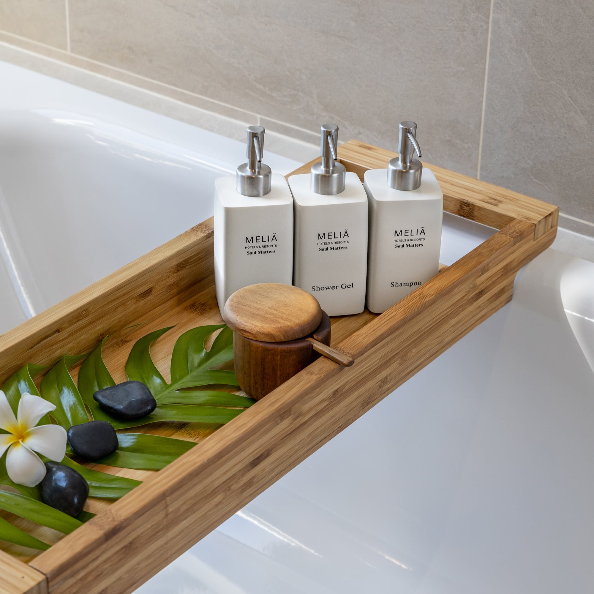 a tray of white bottles and green leaves on a bathtub