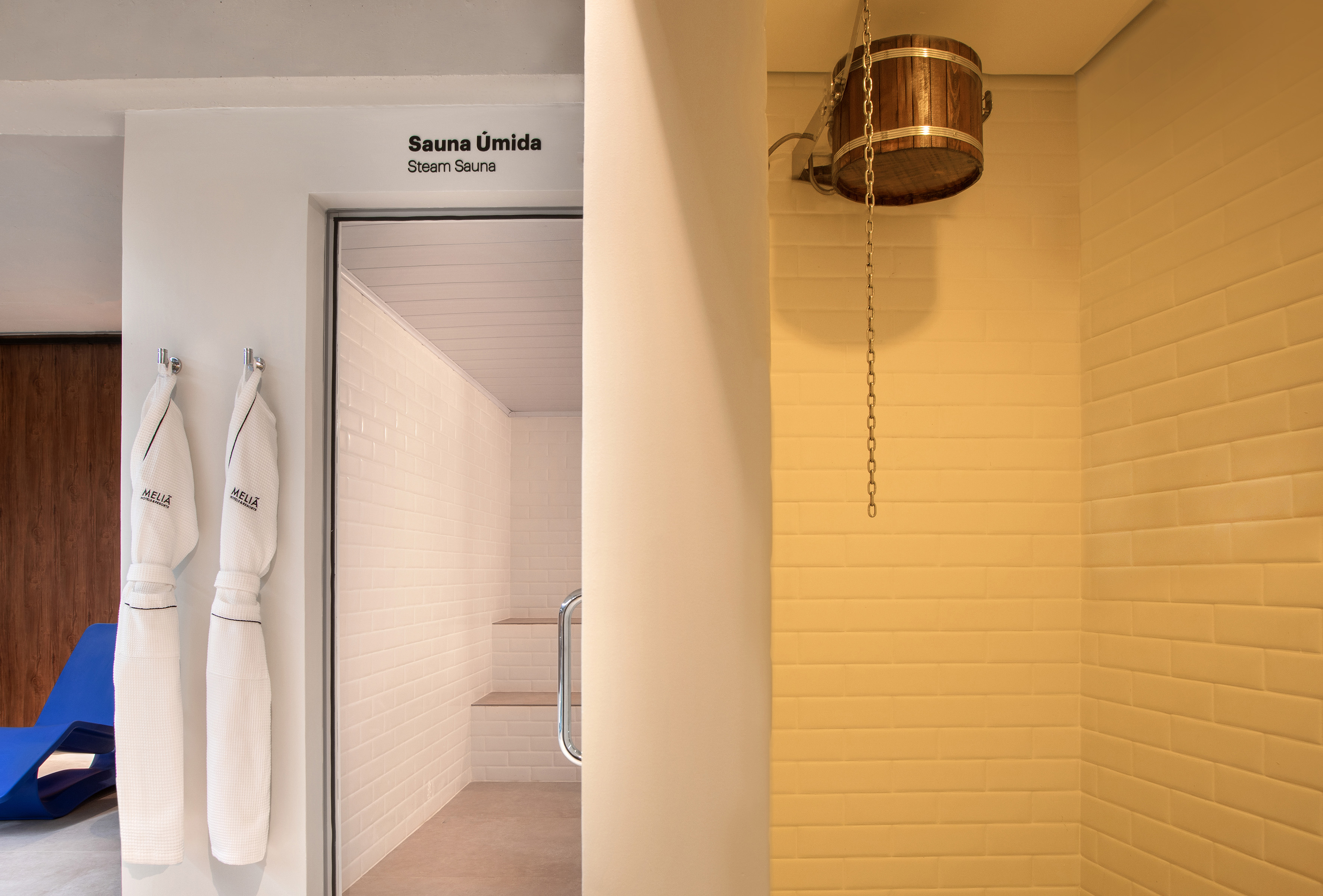 Meliá hotel steam sauna entrance with white bathrobes and wooden bucket.