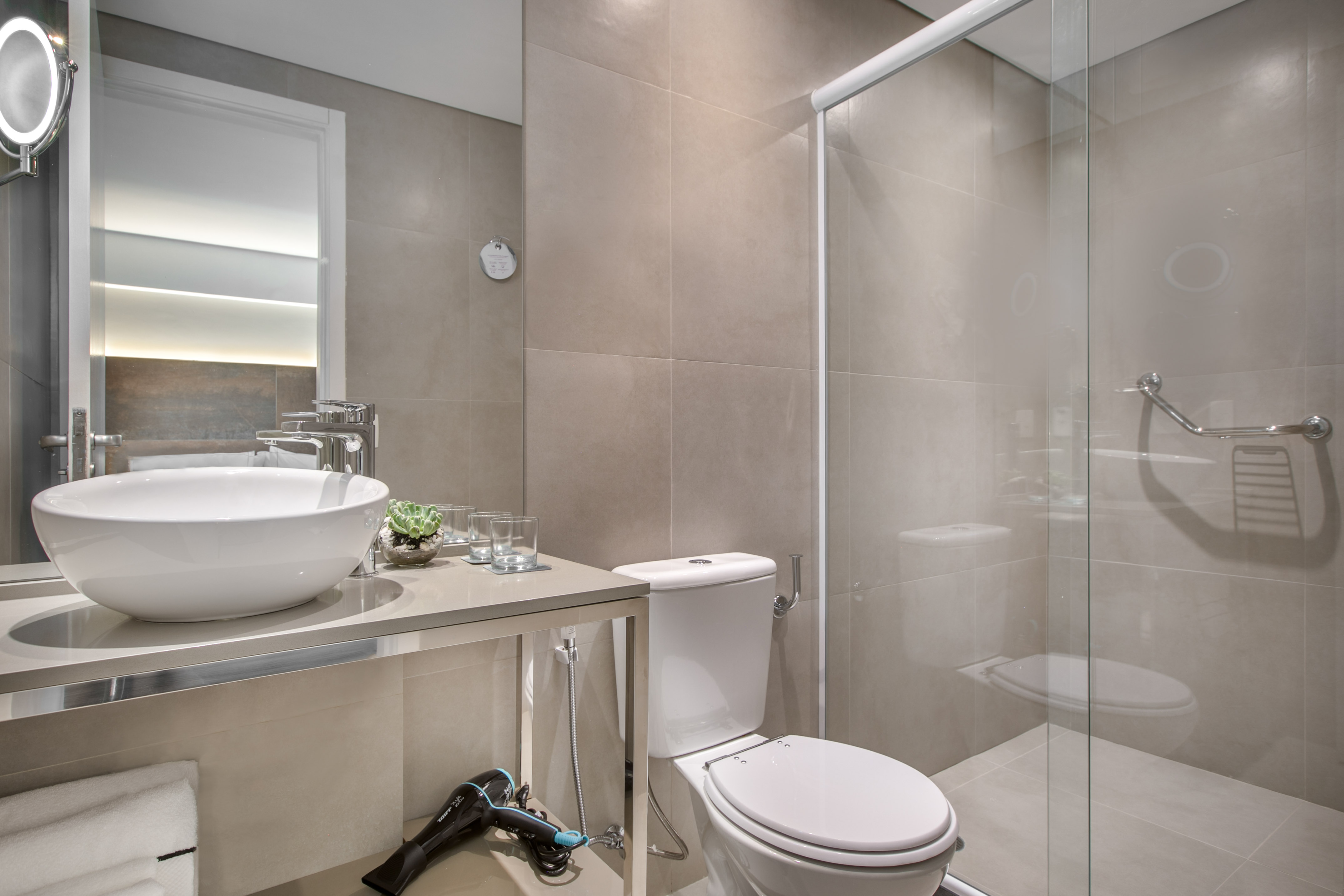 Neutral modern bathroom with vessel sink, toilet, and glass shower.