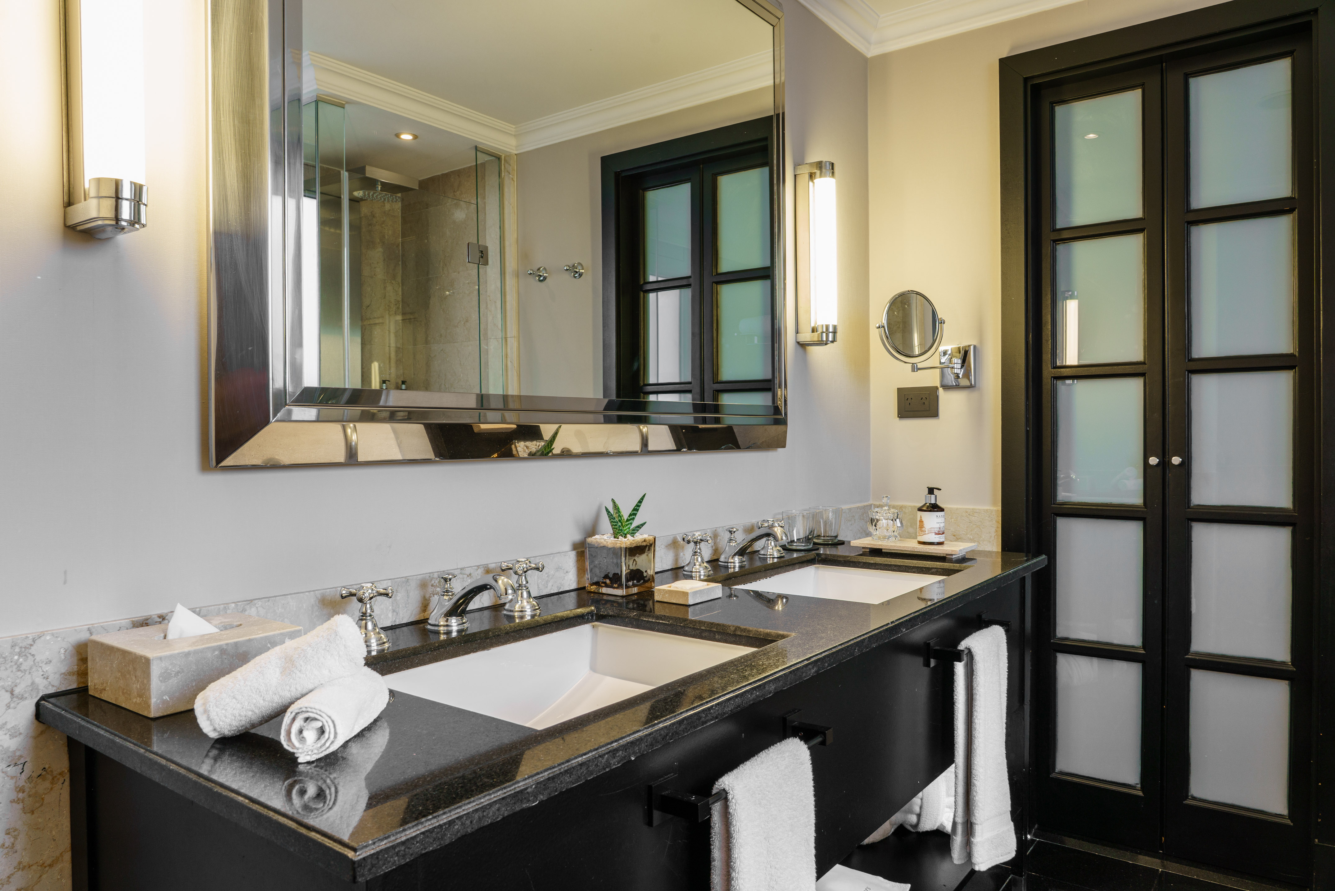 Elegant bathroom with double sinks, black vanity, and large mirror.